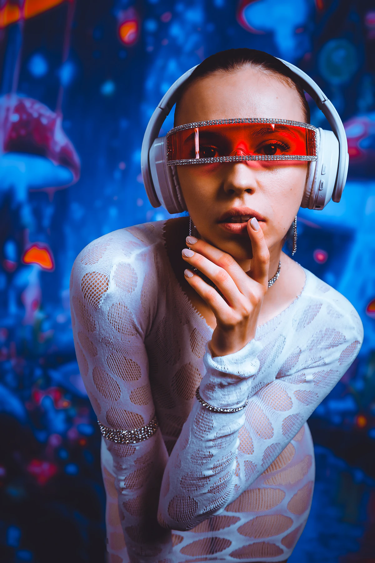 Woman in white headphones and red visor glasses against a neon blue background