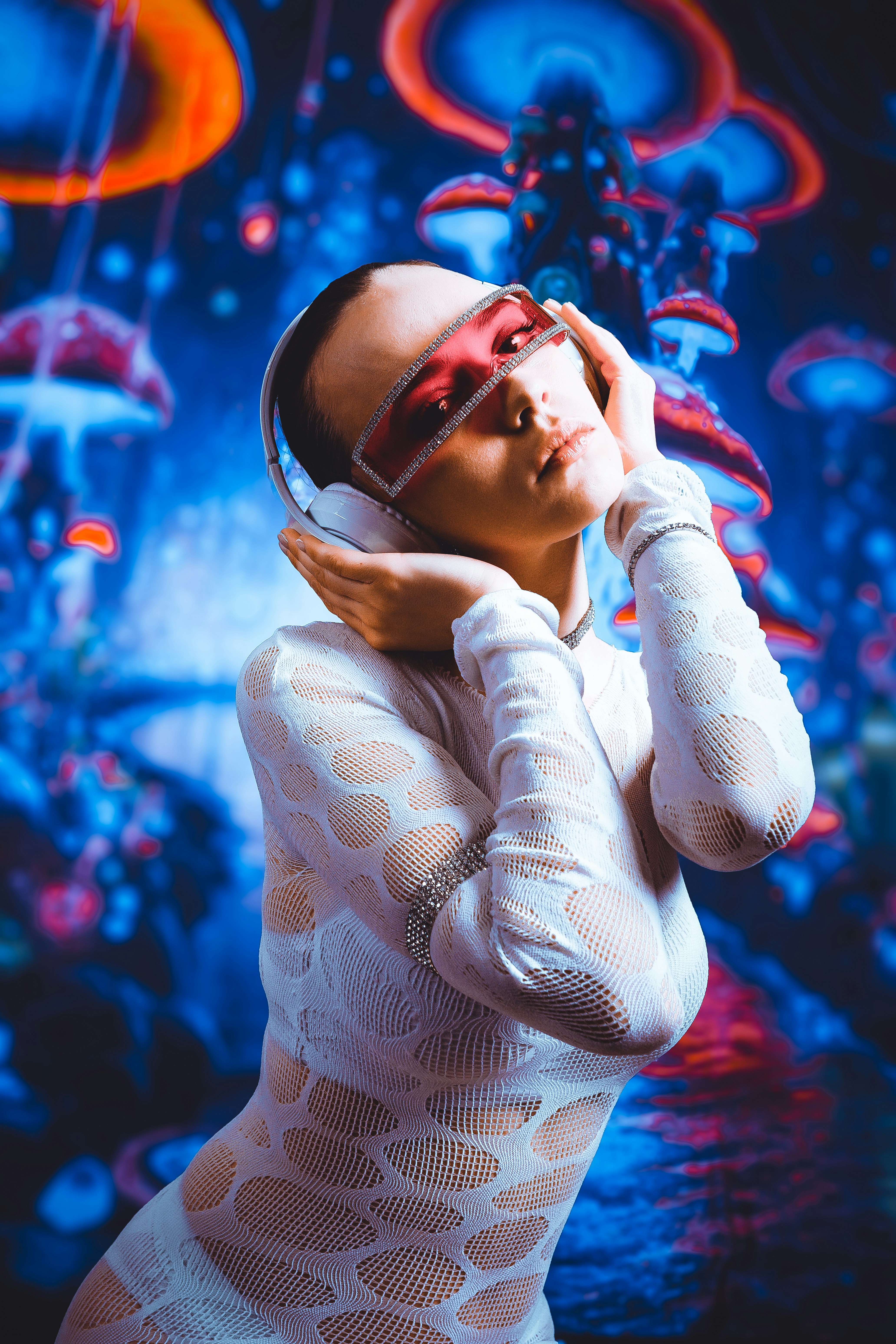 A woman in a white mesh bodysuit wearing red visor glasses and headphones