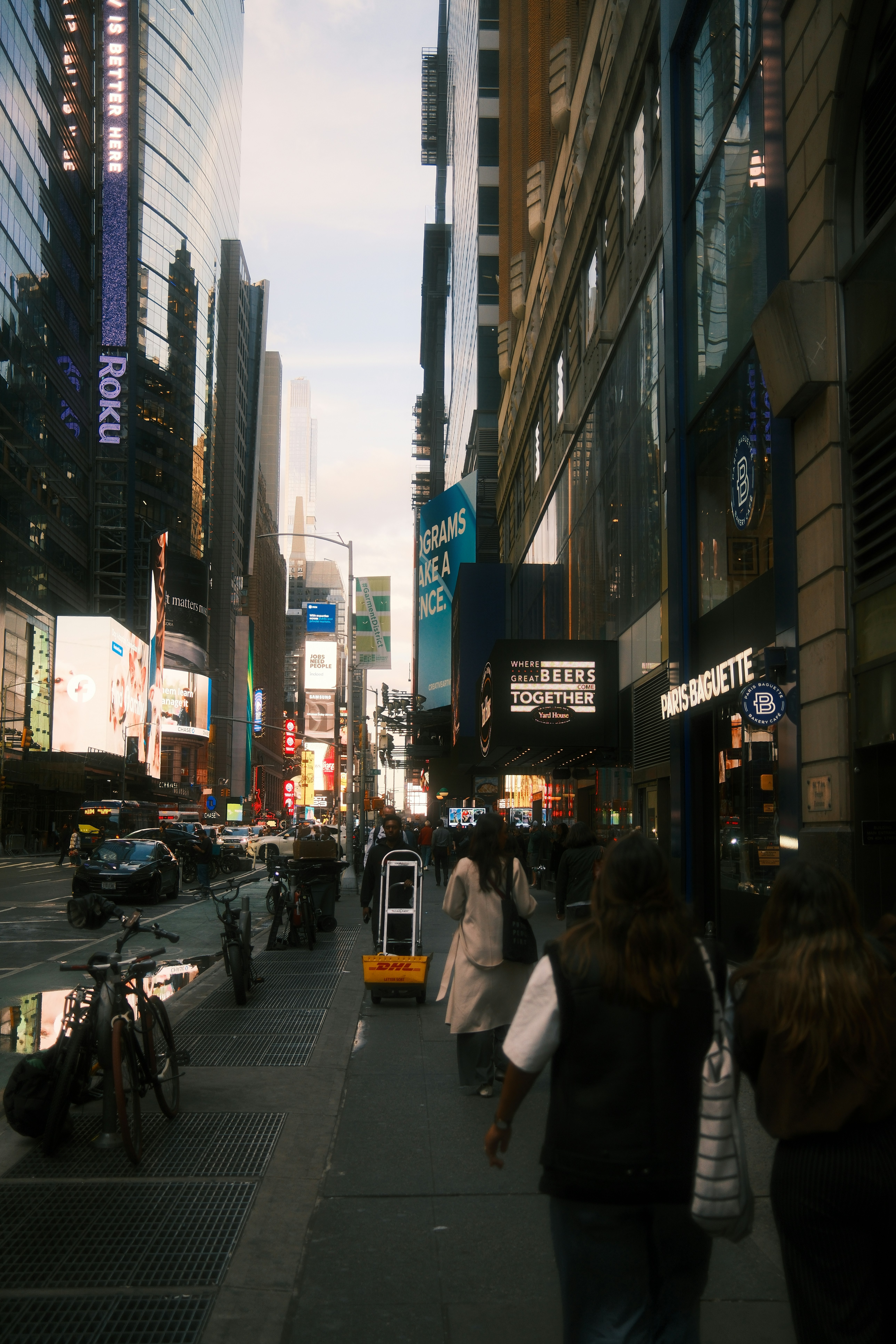 People walking on a busy sidewalk in New York City with tall buildings