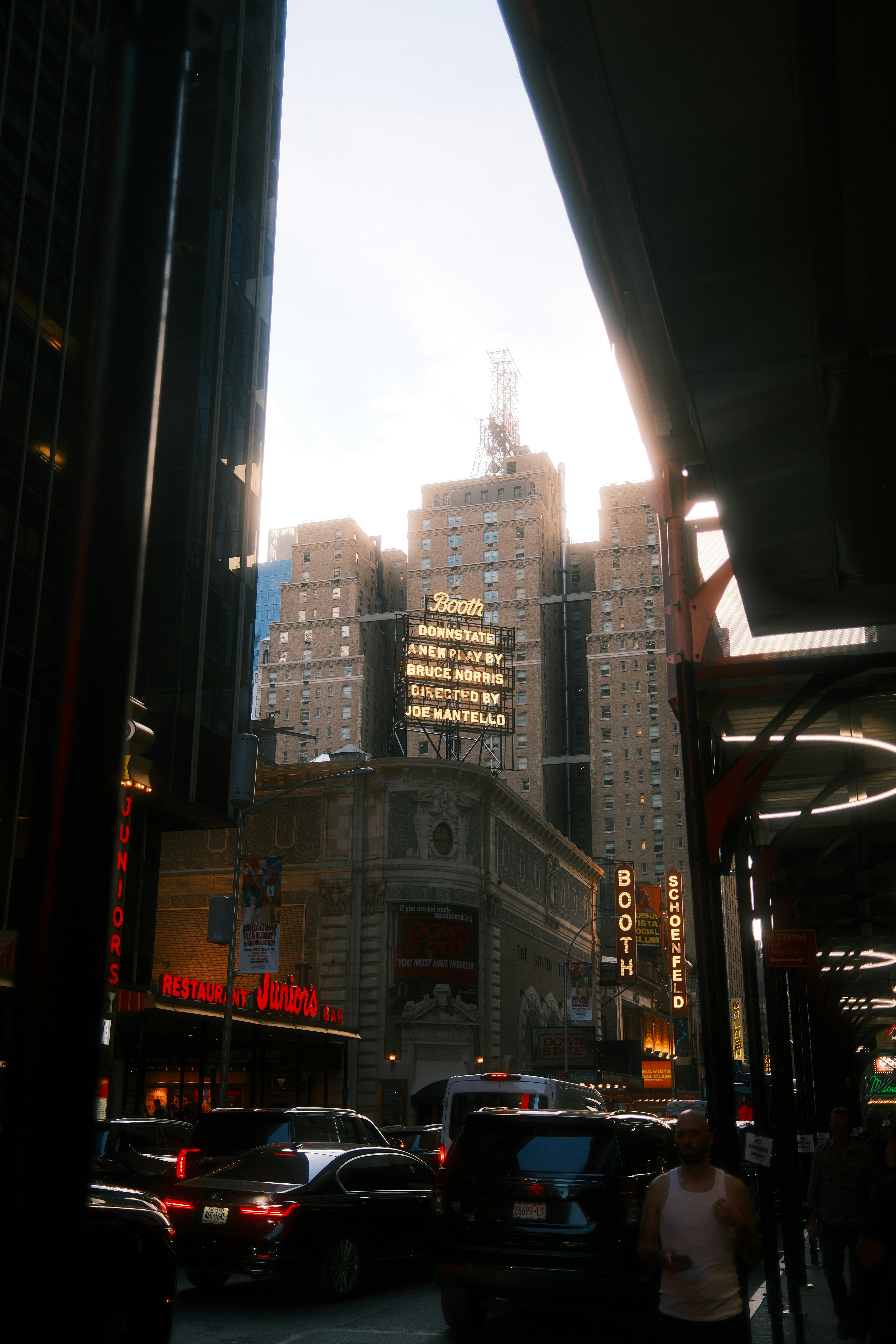 Traffic on a street in New York City with the illuminated Booth Theatre marquee