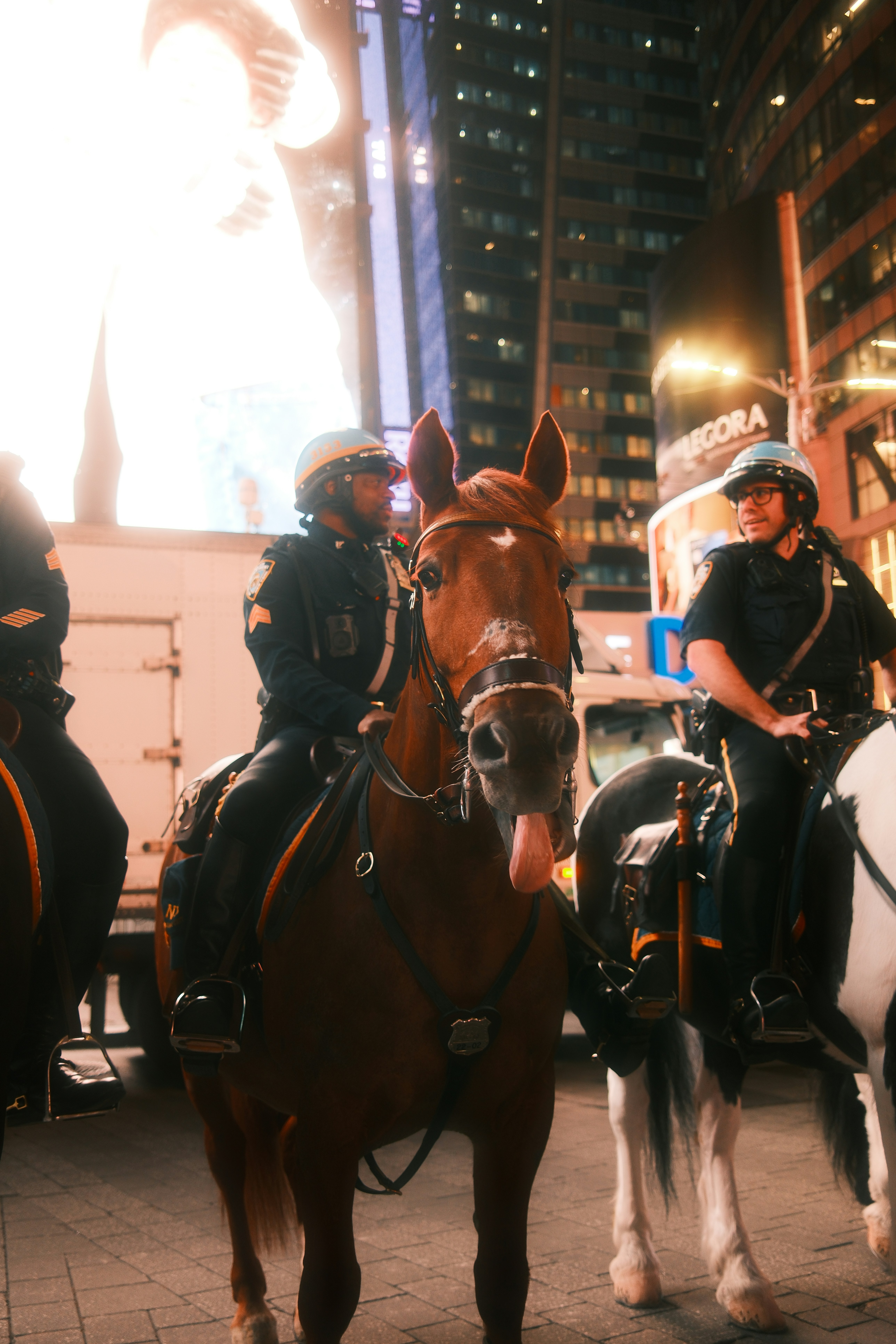 Mounted police officers on horses in Times Square at night with bright digital billboards