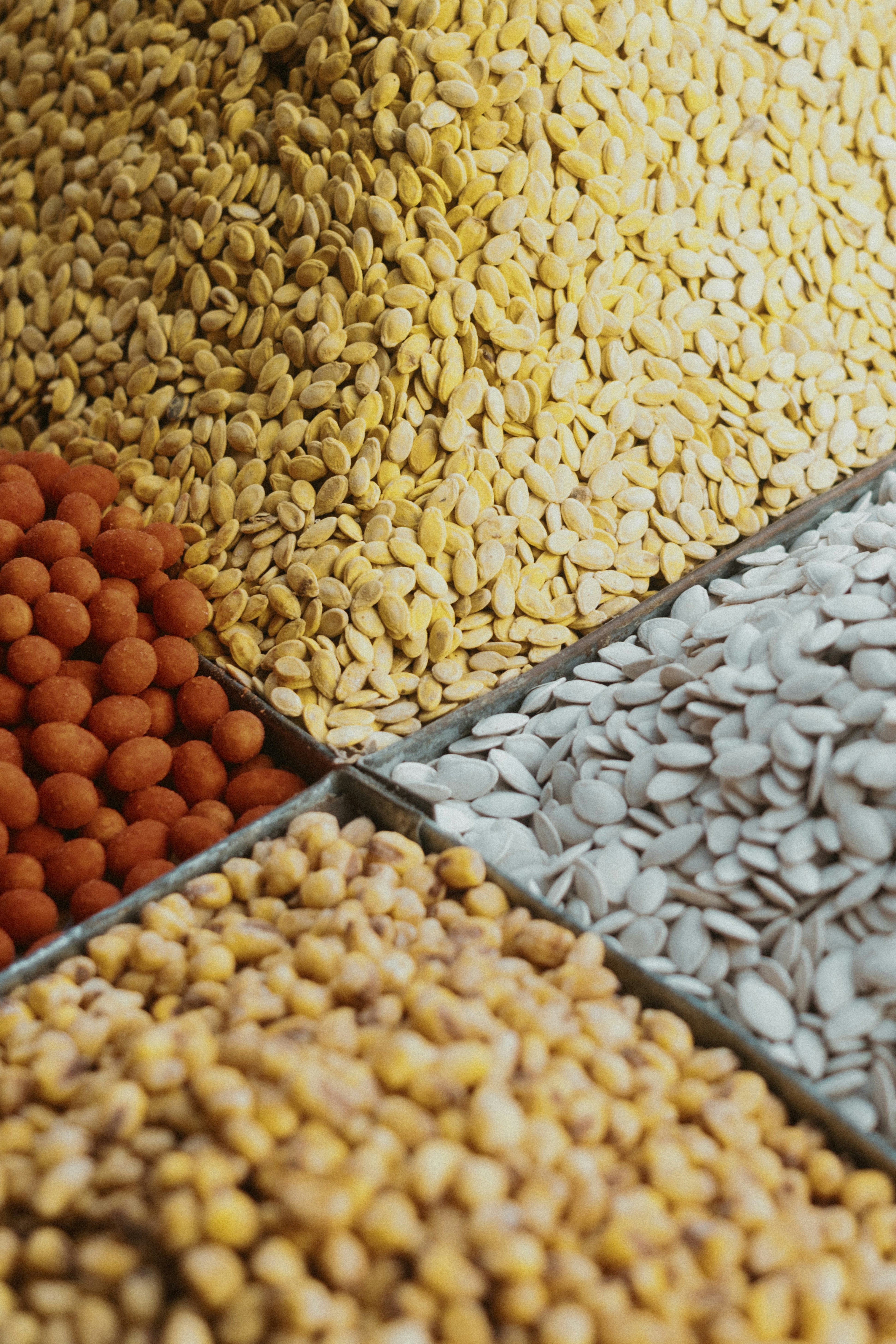 Four piles of assorted nuts and seeds in a metal container