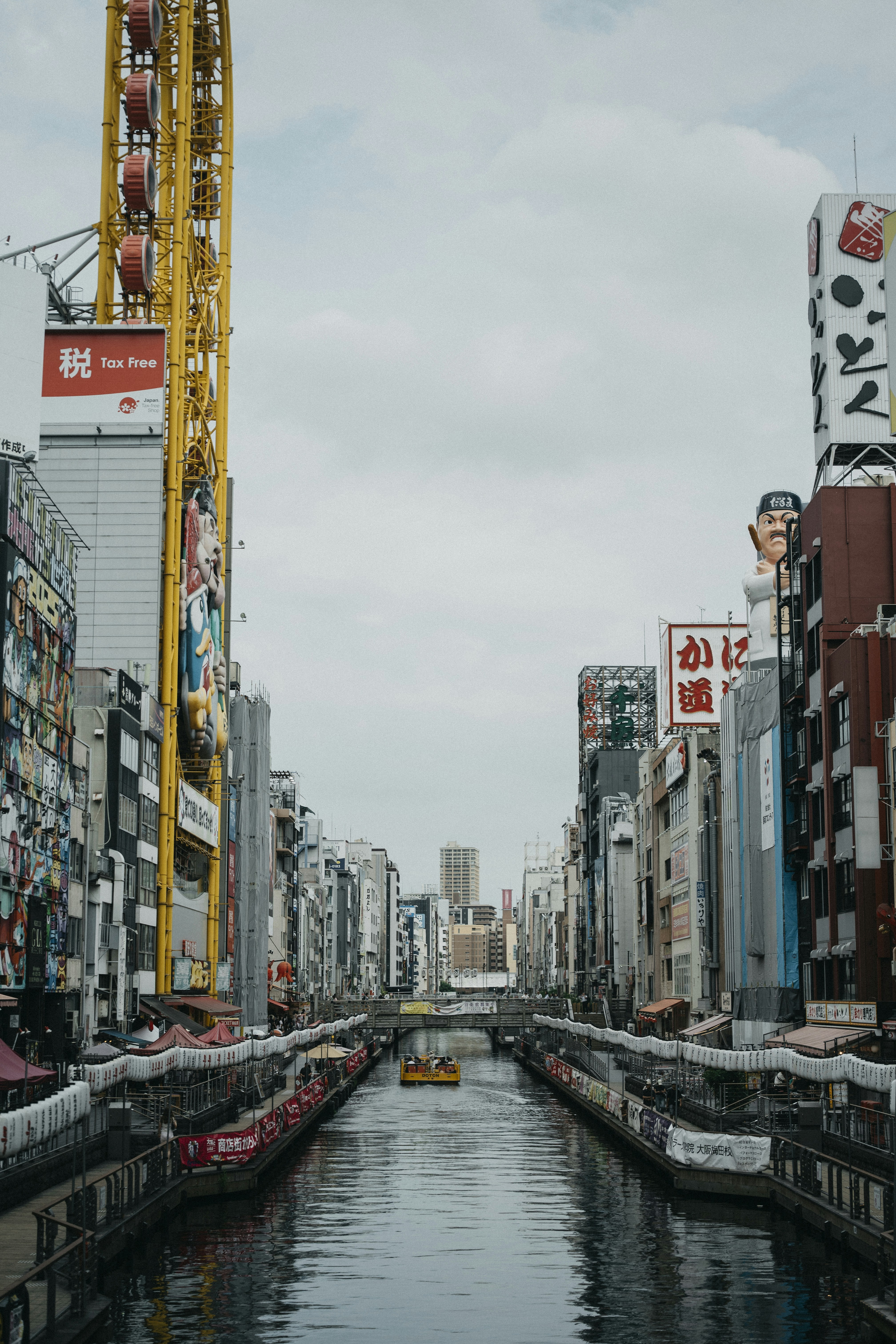 A boat on the Dotonbori canal in Osaka lined with tall buildings and signage