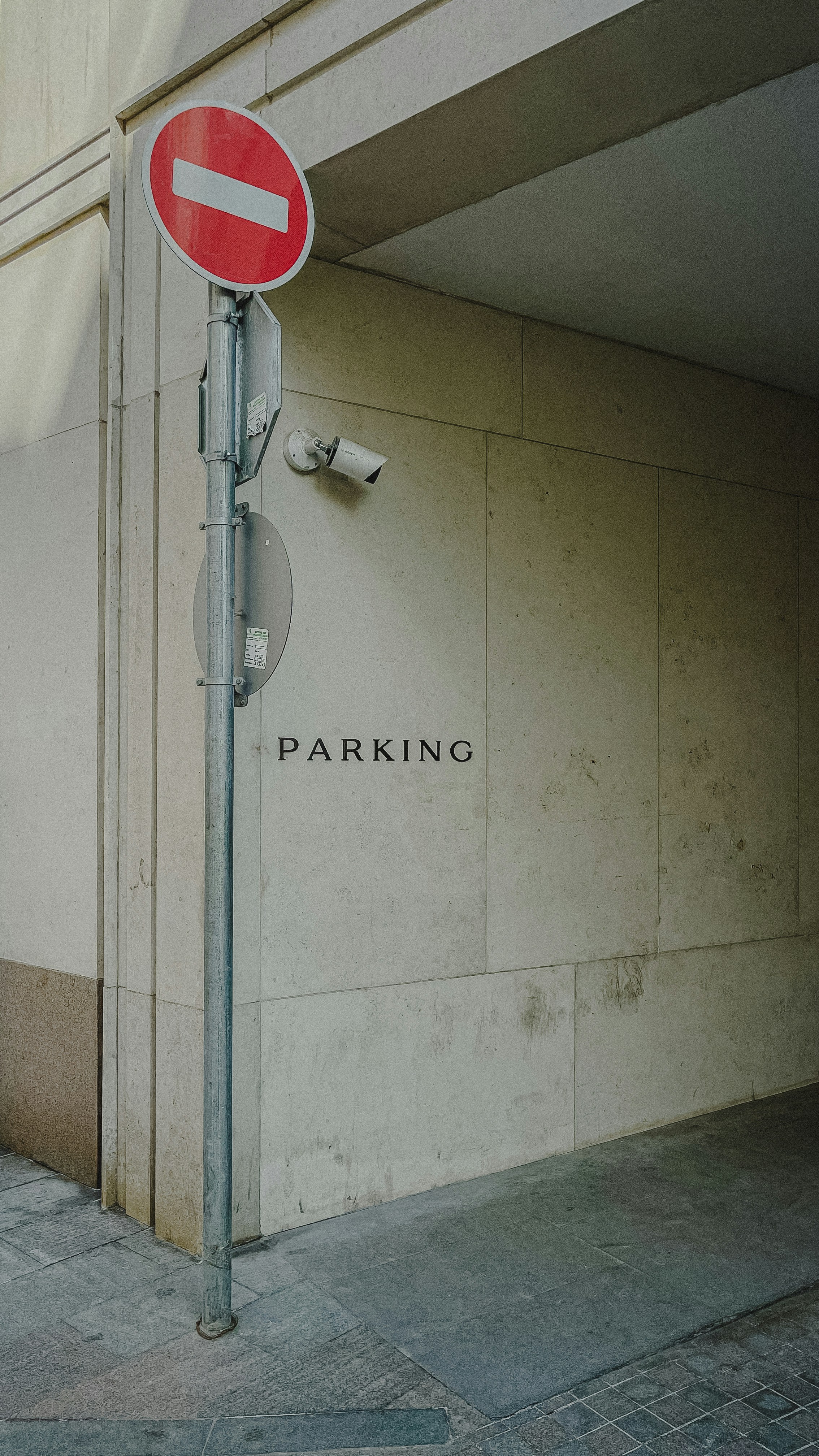Un cartel de prohibido la entrada y una cámara de seguridad en una pared señalizada como aparcamiento