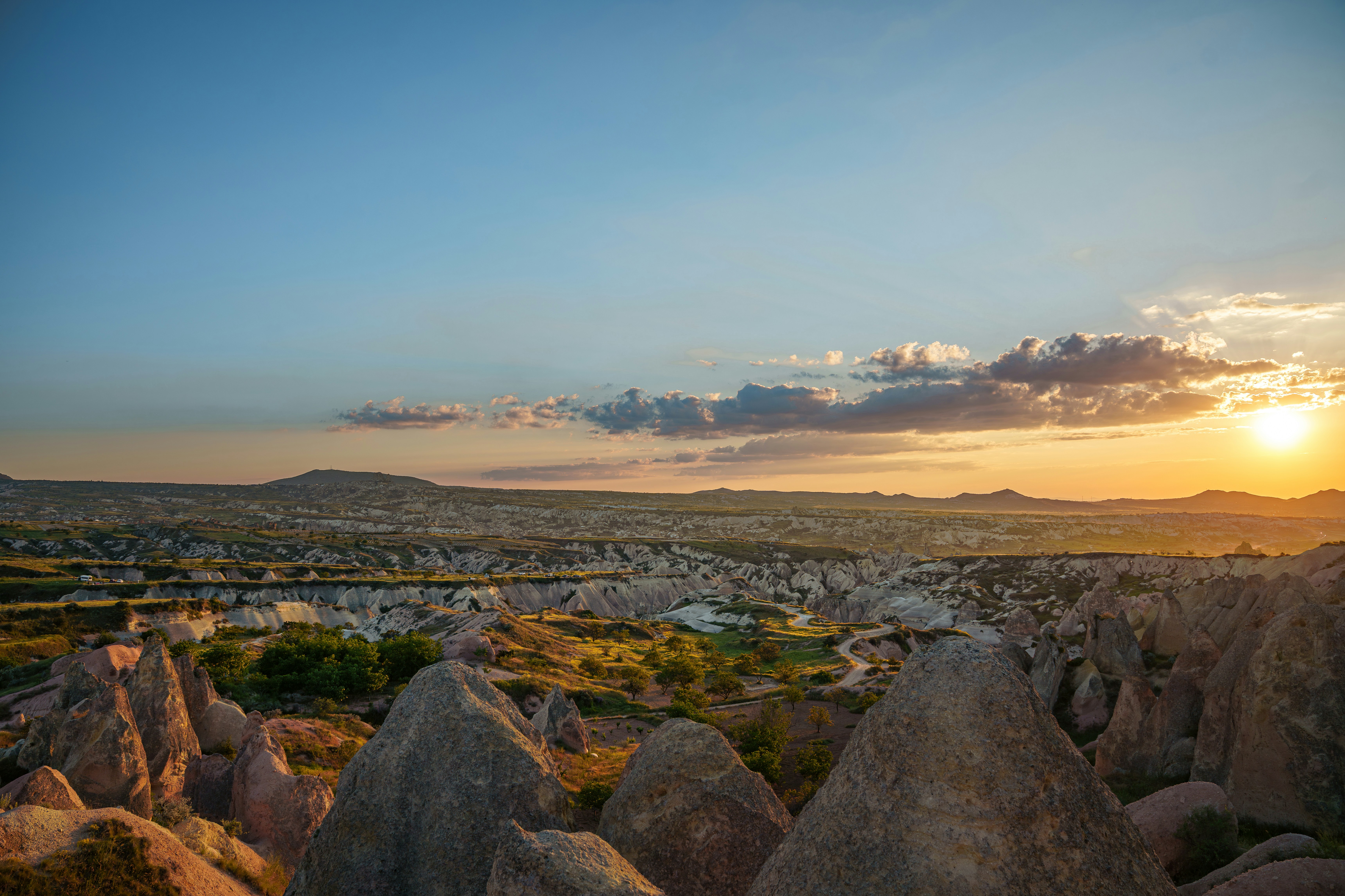 Rocky landscape with conical formations under a warm sky with low sun