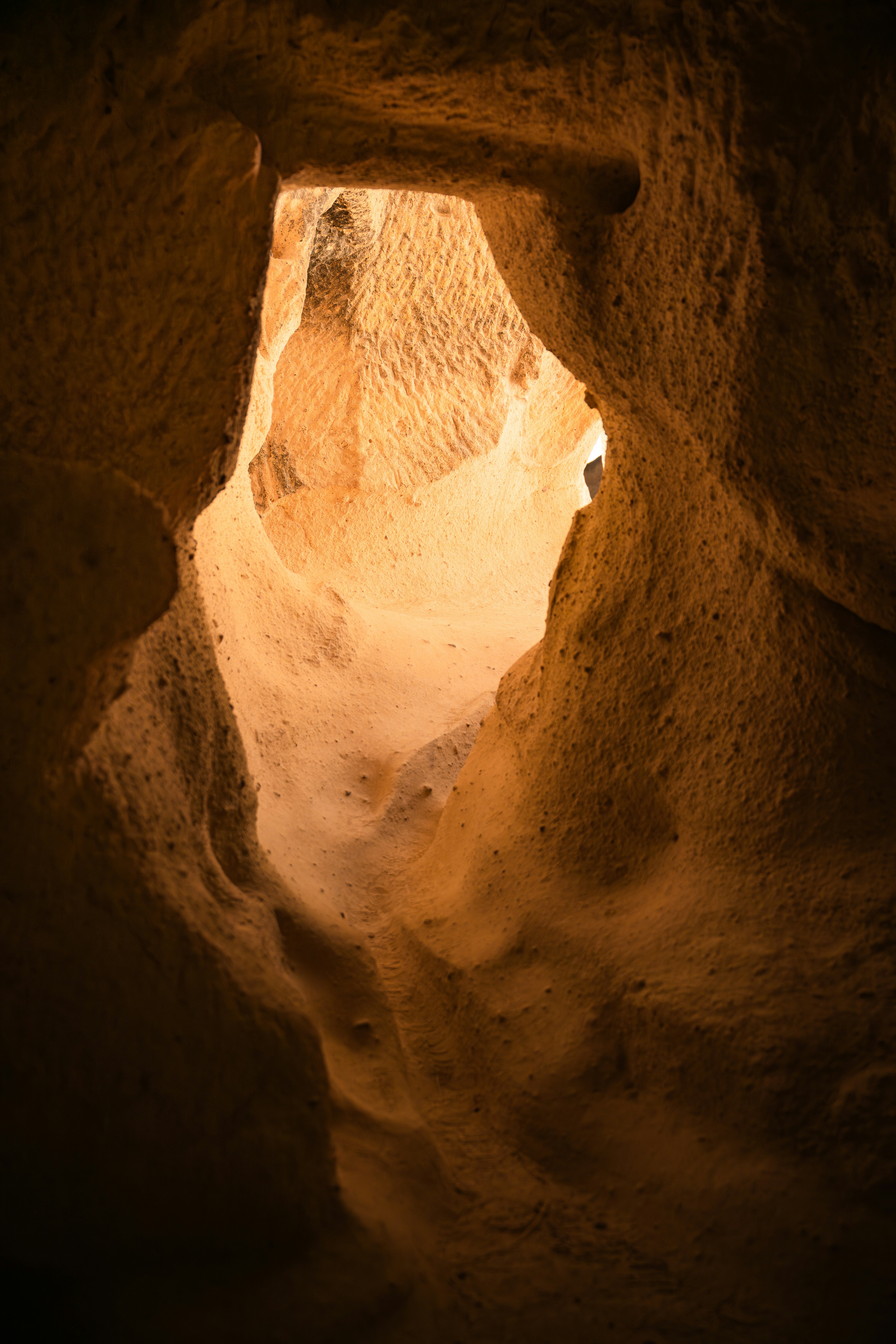 A narrow passage through textured golden sandstone walls illuminated by warm light