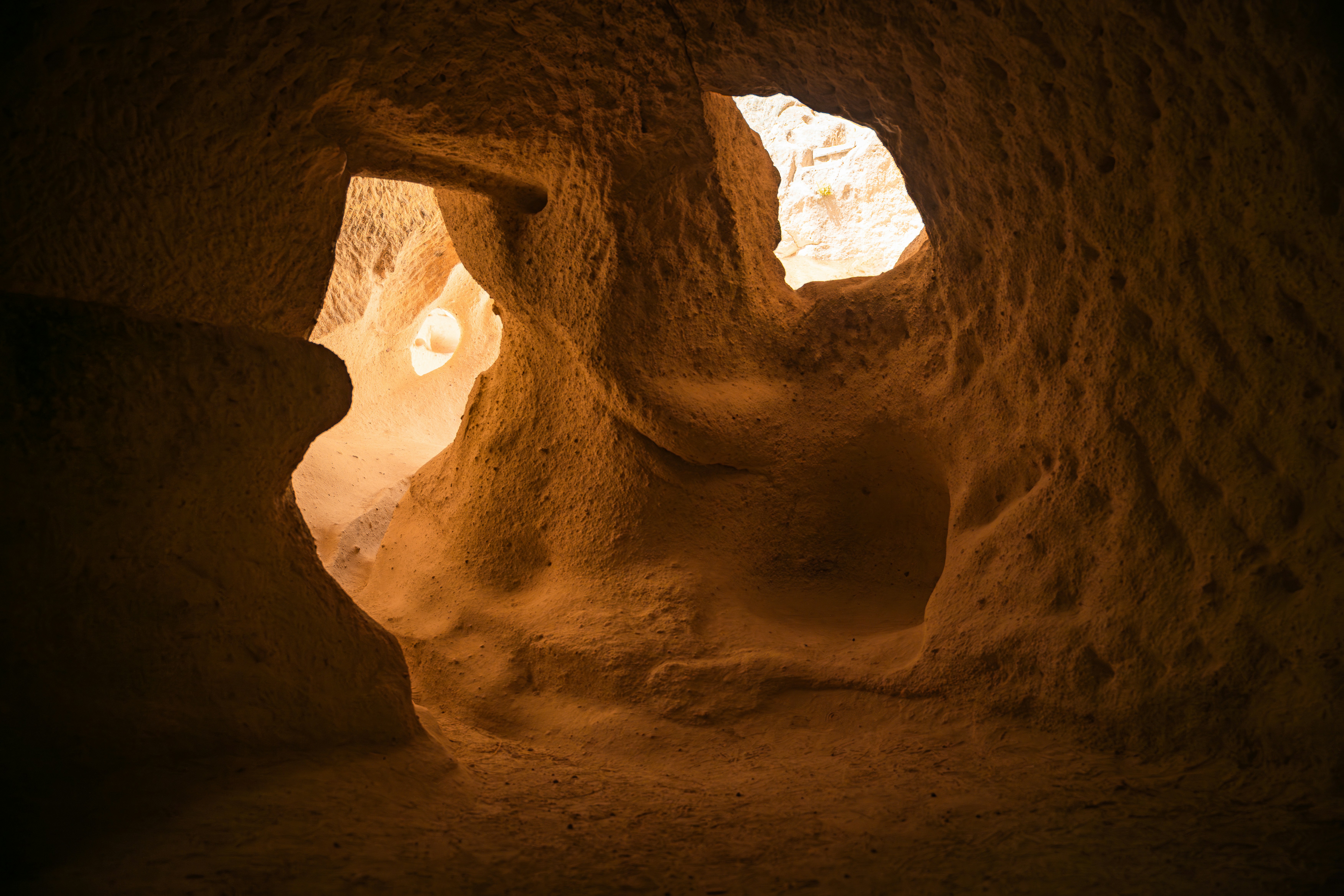 Natural light illuminating the interior of a textured orange sandstone cave