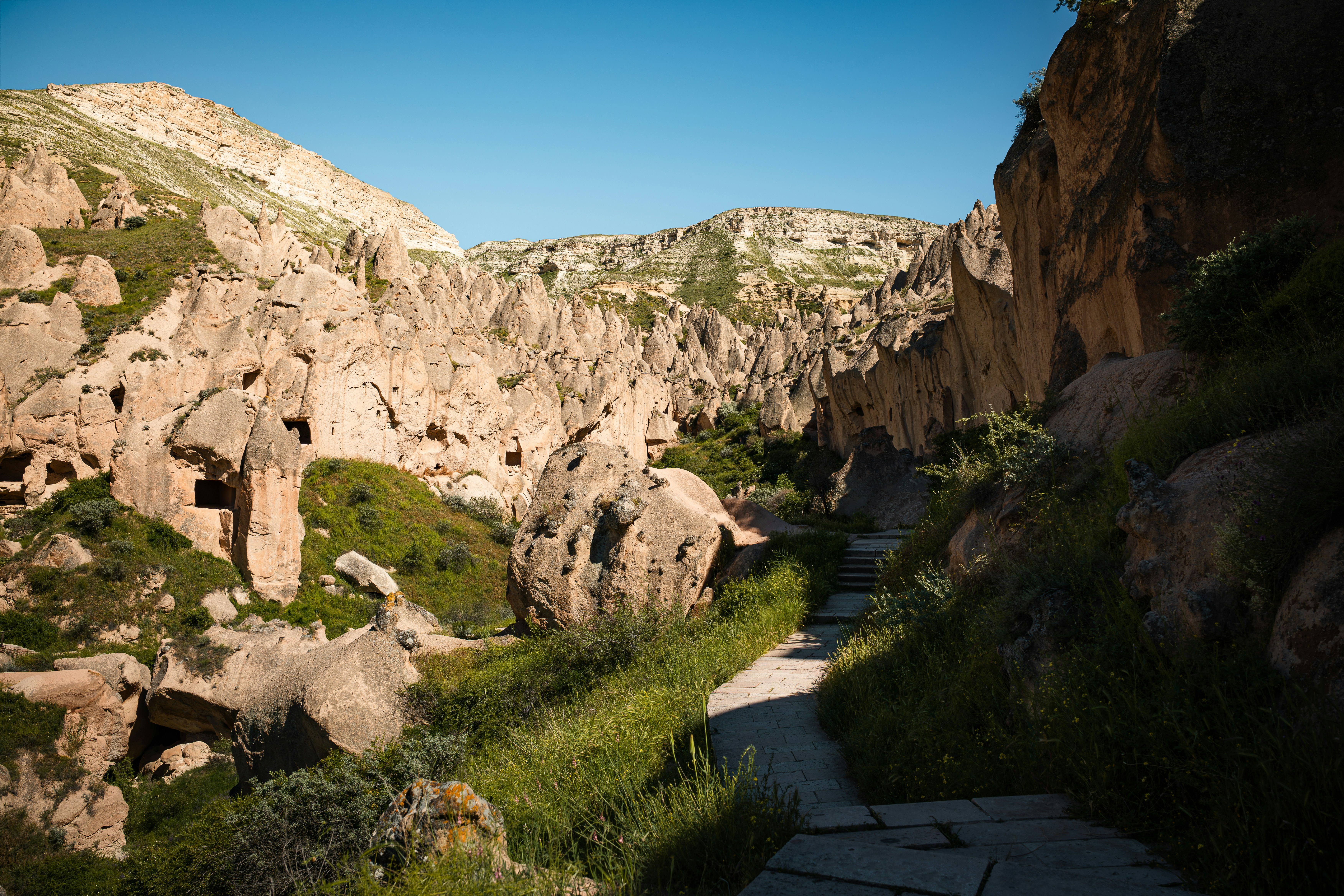 A stone path winding through a valley of carved rock formations in Cappadocia