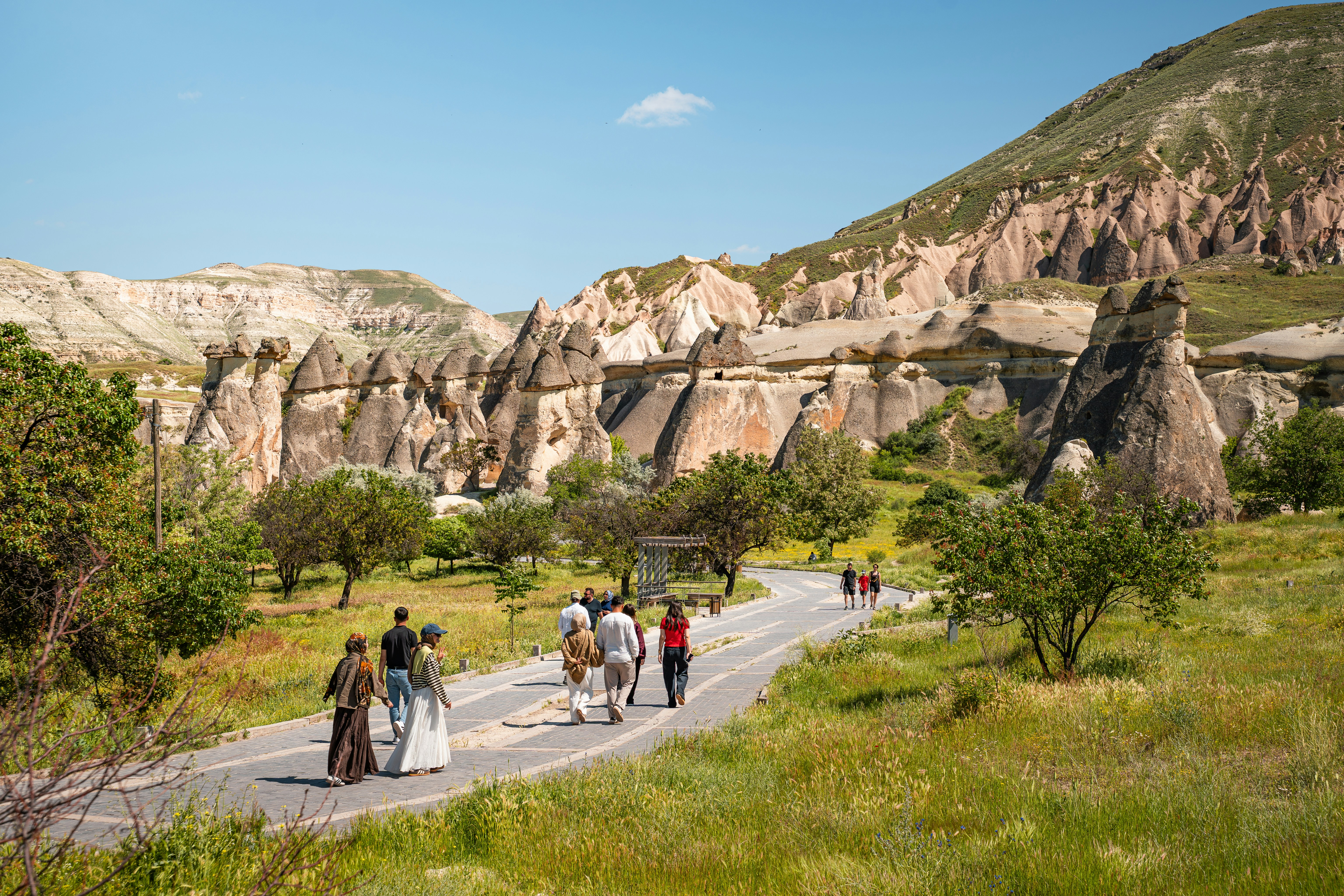 People walking on a paved path through the fairy chimneys of Cappadocia, Turkey