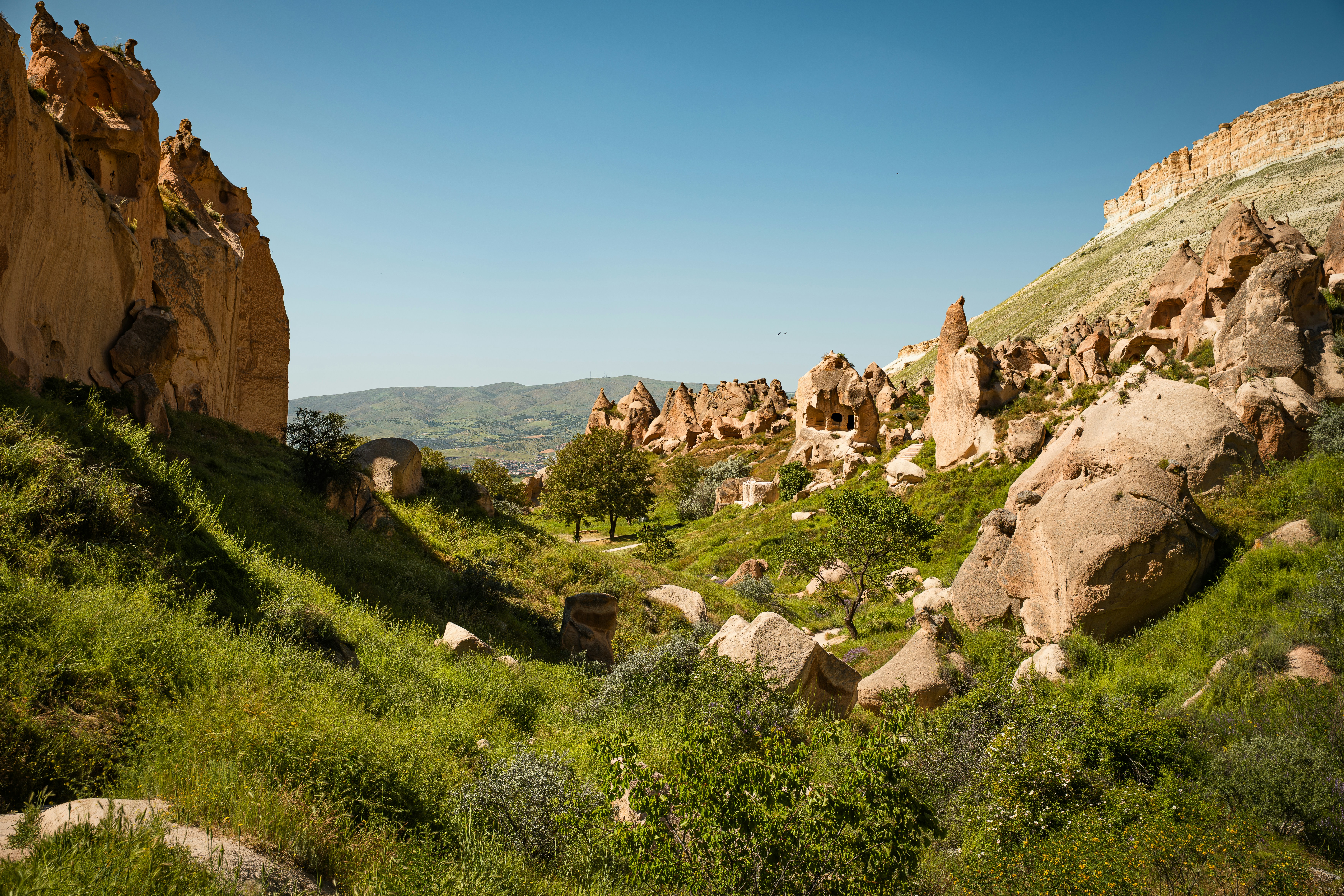 Eroded rock formations and green grassy slopes in the valley of Cappadocia, Turkey