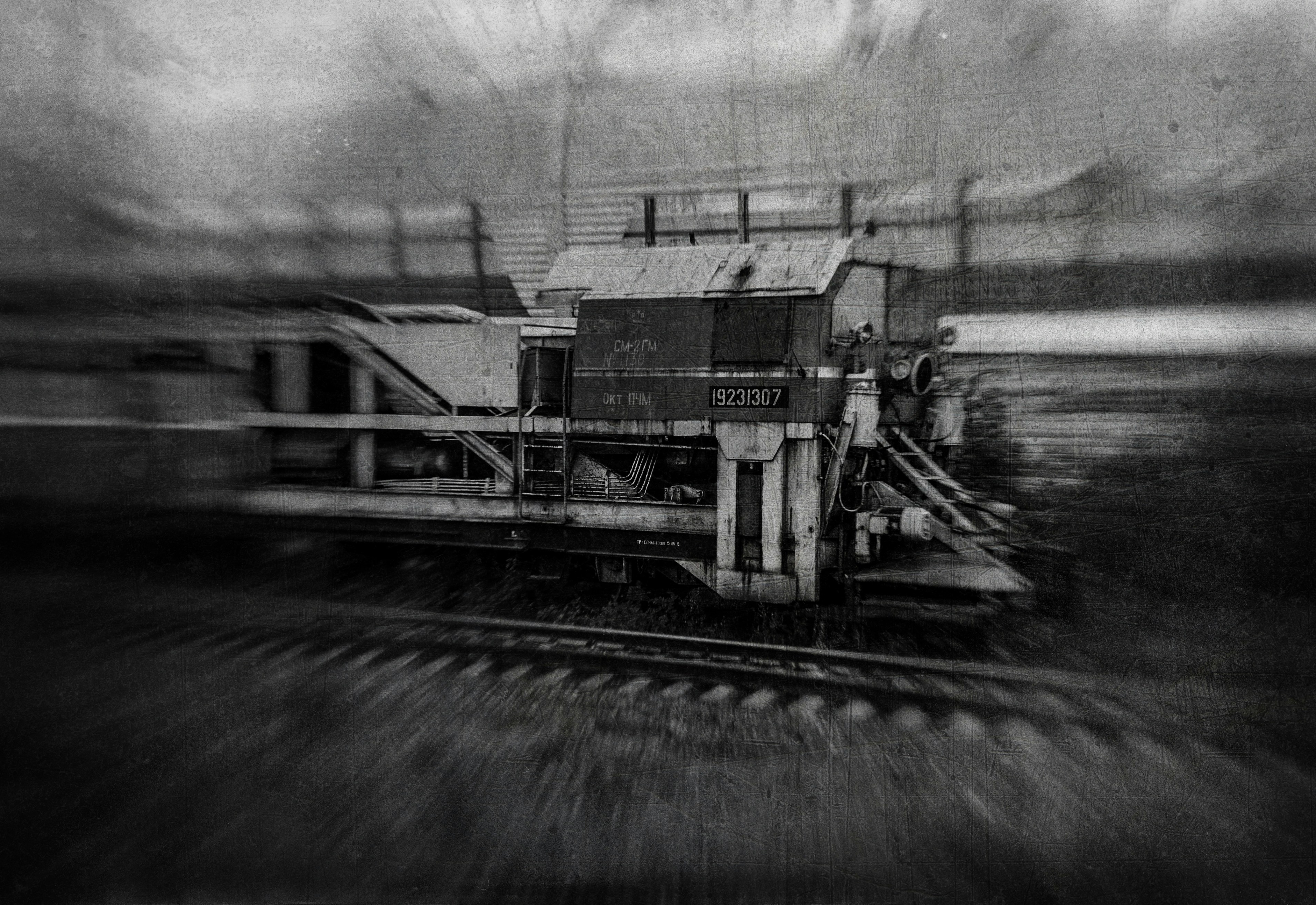 A black and white motion blur of a railway maintenance vehicle on tracks