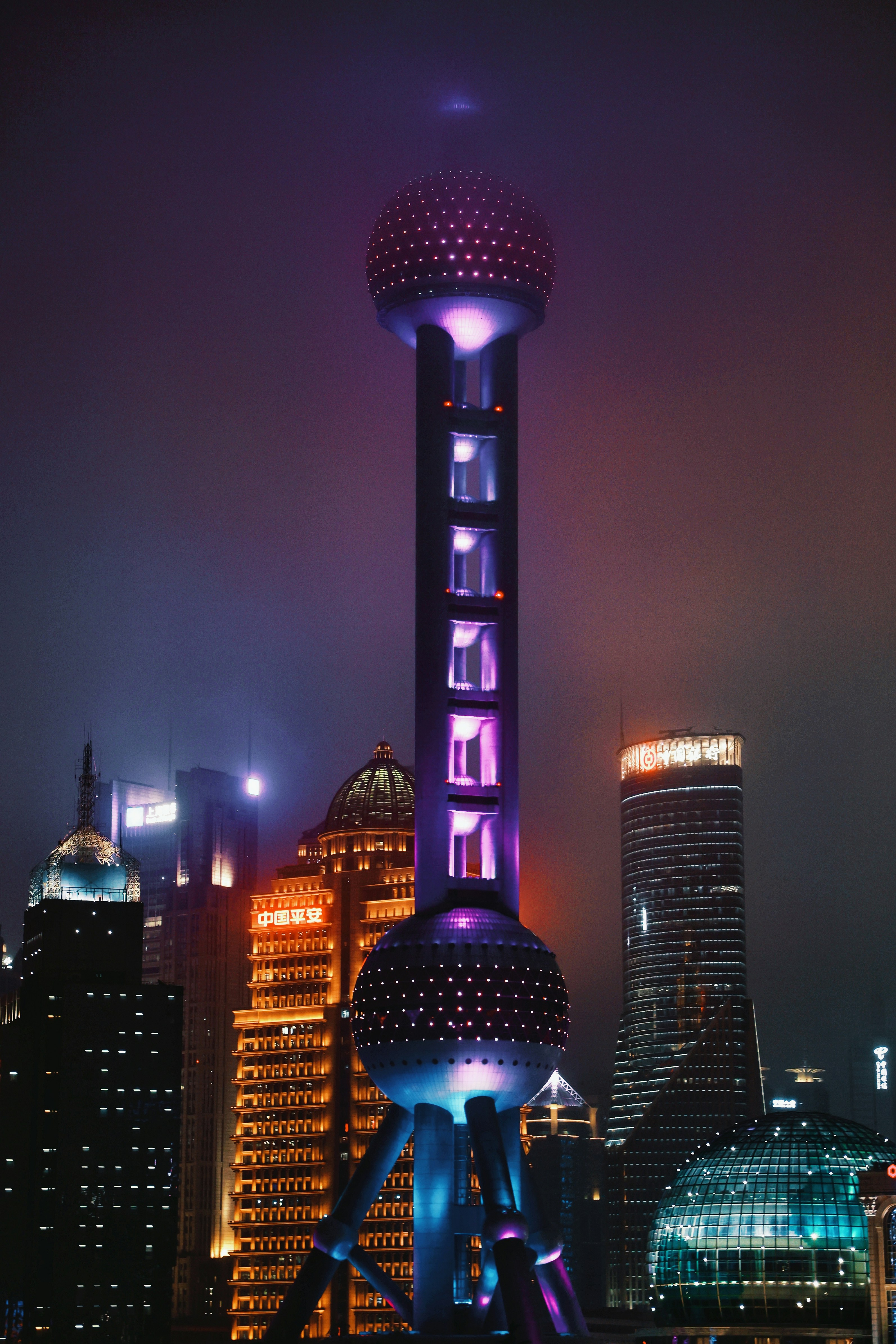 The Oriental Pearl Tower illuminated in purple light among skyscrapers in Shanghai at night