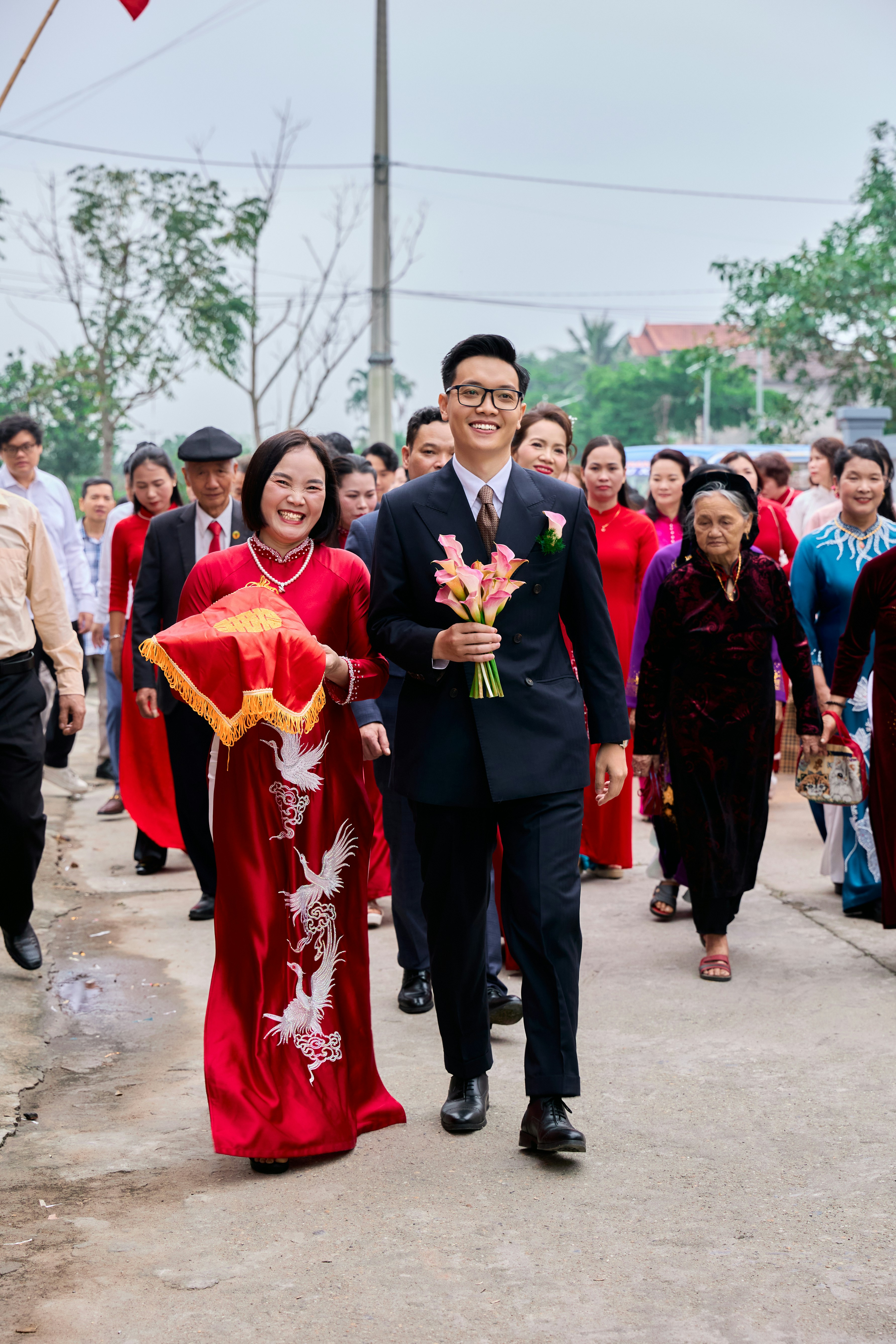 A man in a suit and a woman in a red ao dai walking together