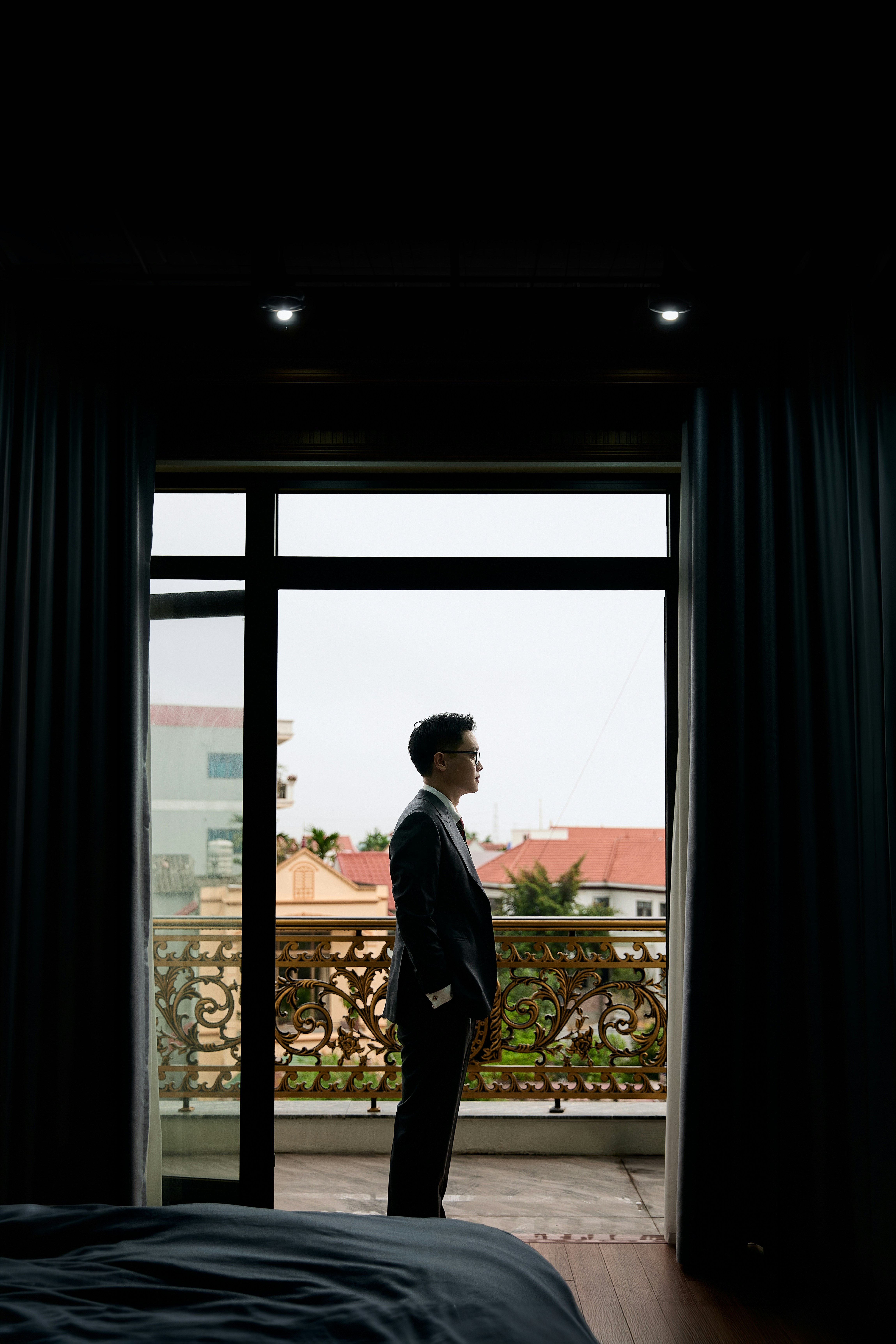 A man in a suit on a balcony overlooking a residential street