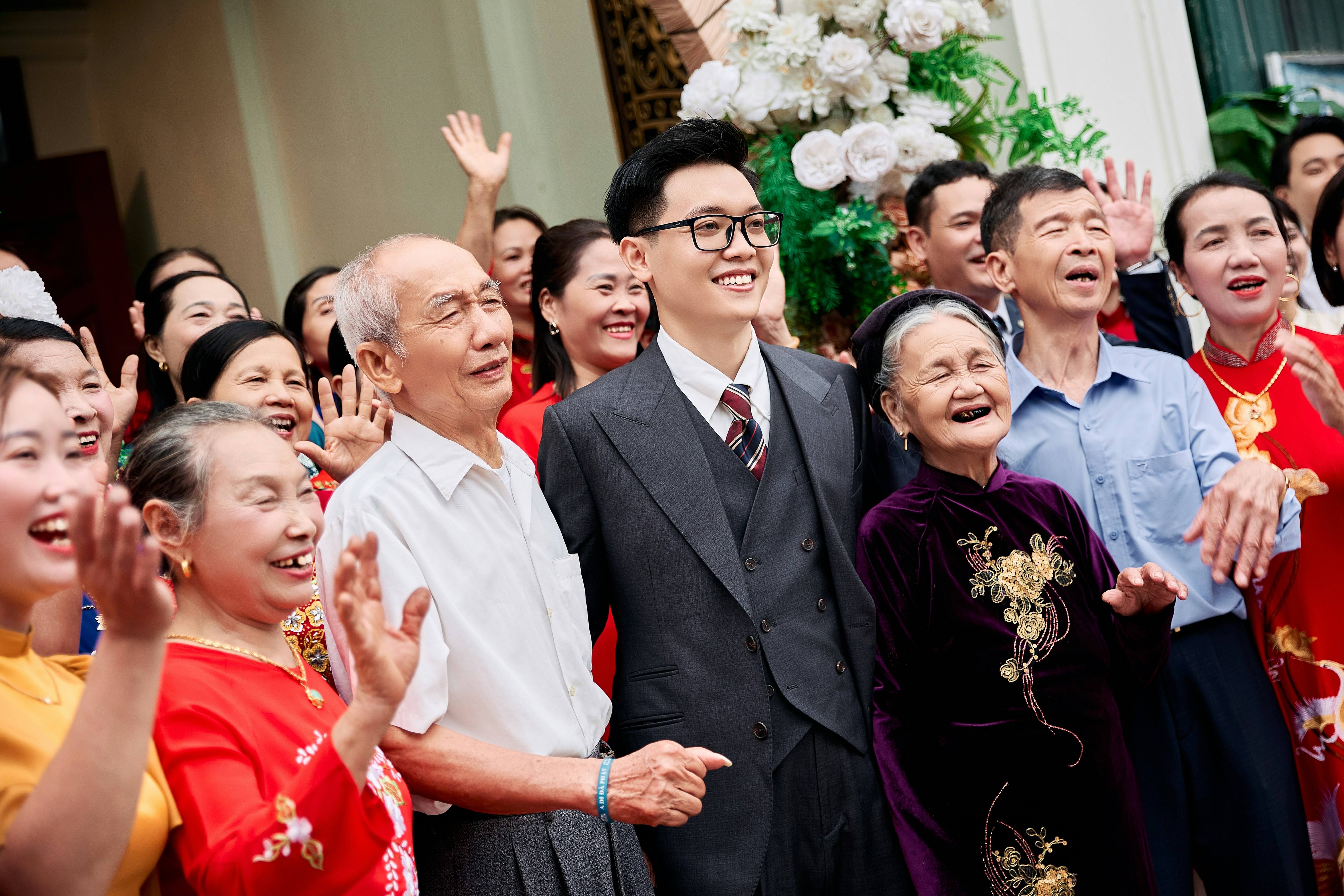 A smiling man in a suit surrounded by a large family at a celebration