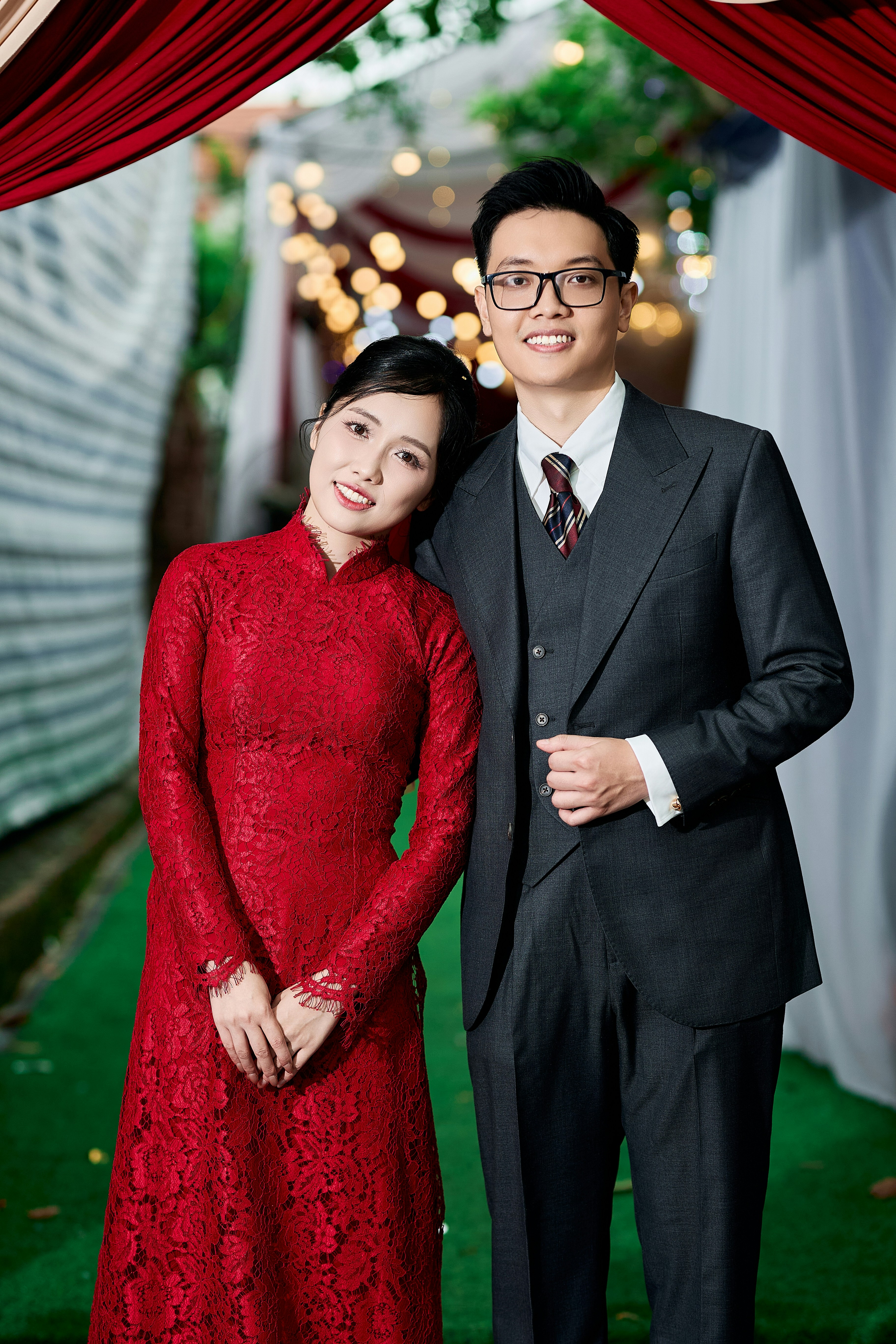 A woman in a red lace dress leaning on a man in a suit