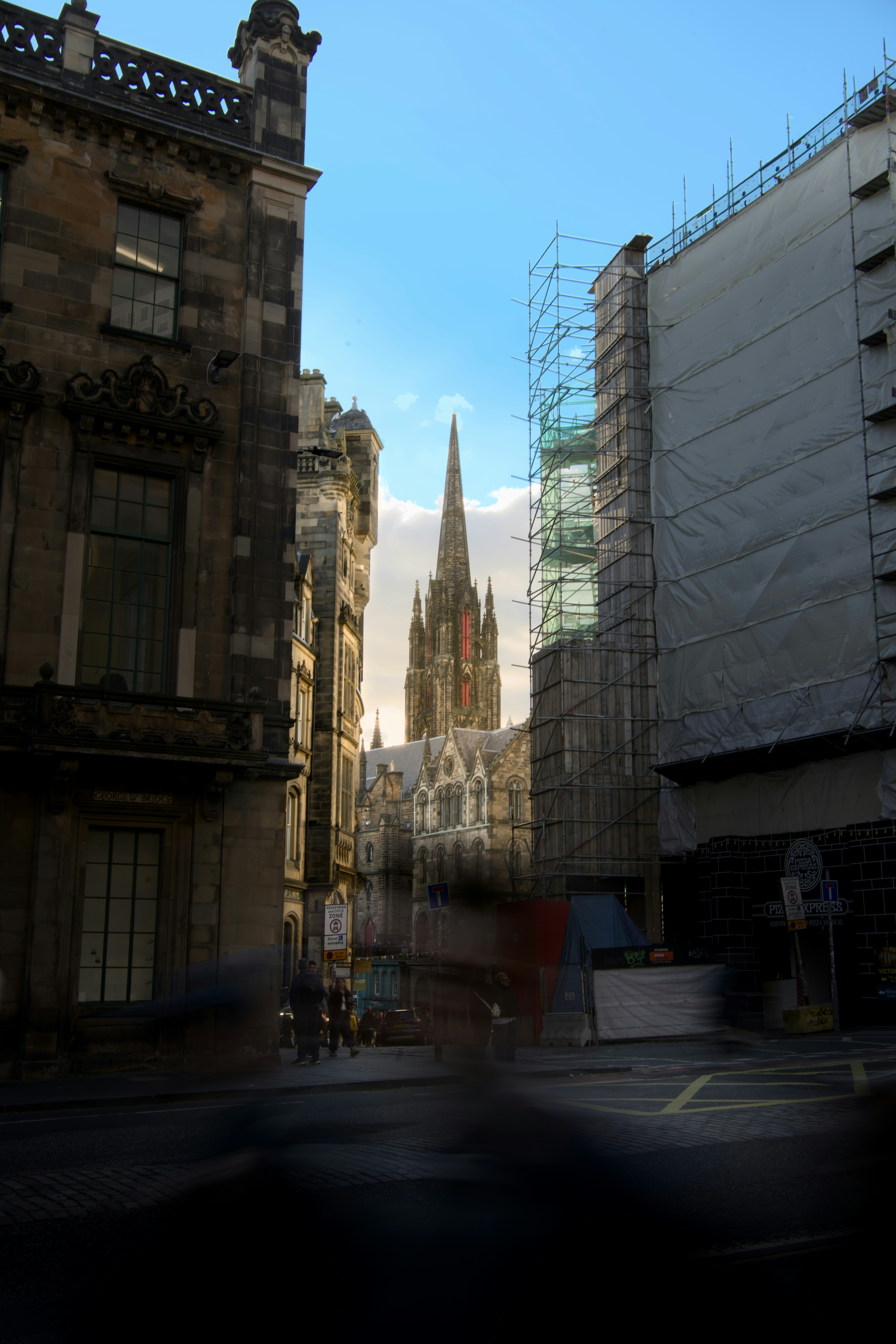 The Hub spire rising above stone buildings in Edinburgh with scaffolding on the right