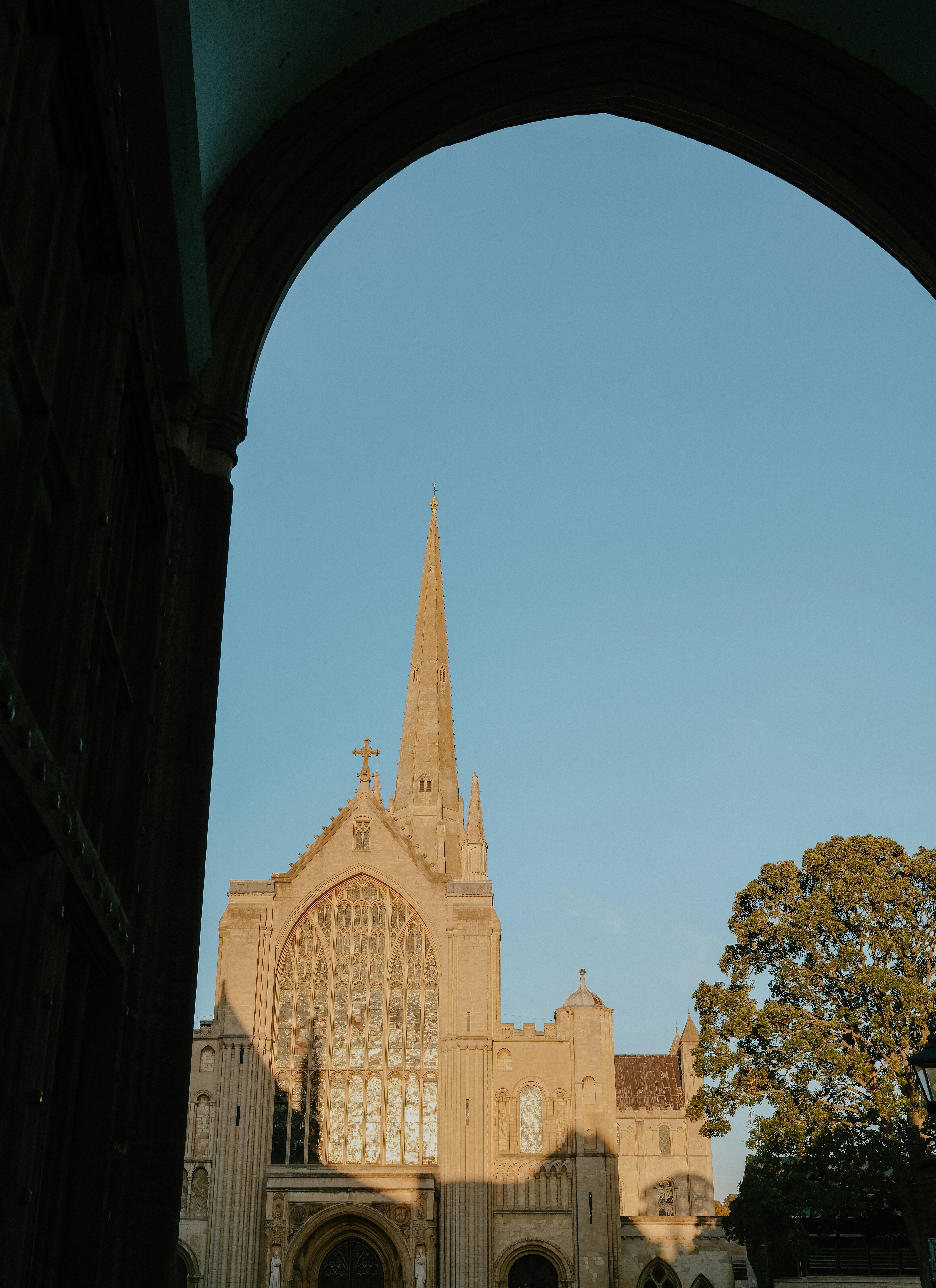 A stone cathedral with a tall spire framed by a dark archway