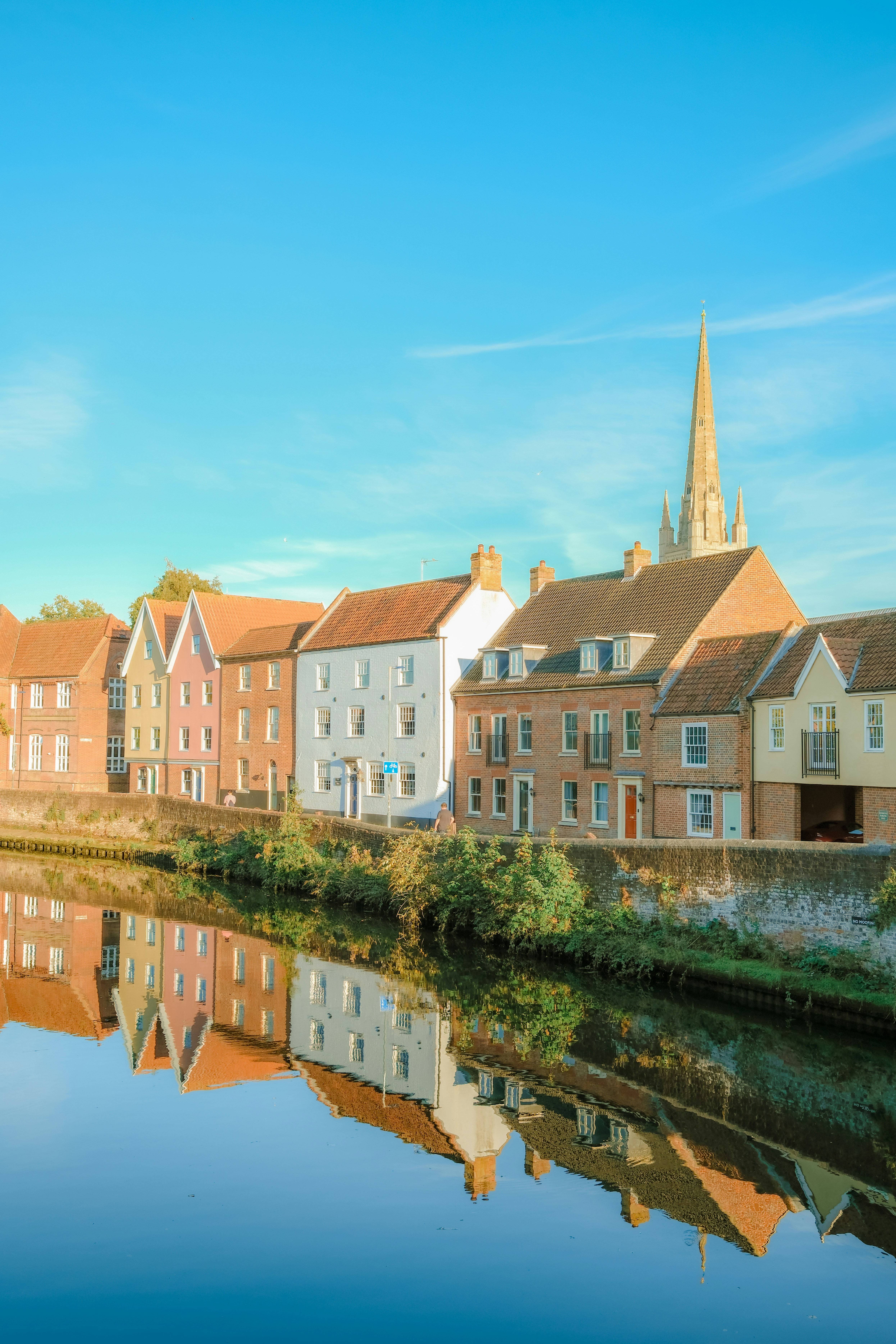 Colorful historic houses reflecting in the calm water of the River Wensum in Norwich