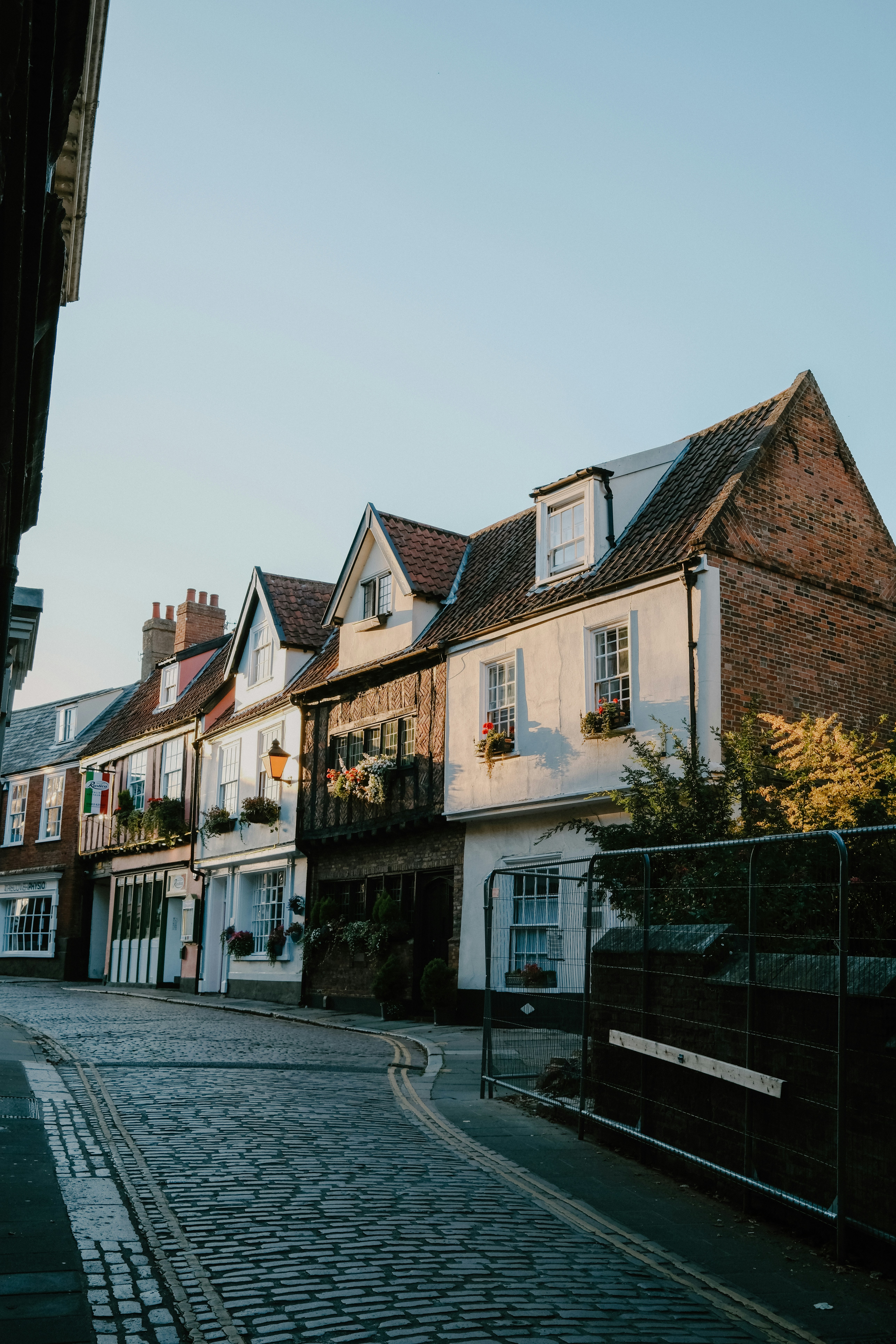 A row of historic timber-framed houses along a cobblestone street in late afternoon light