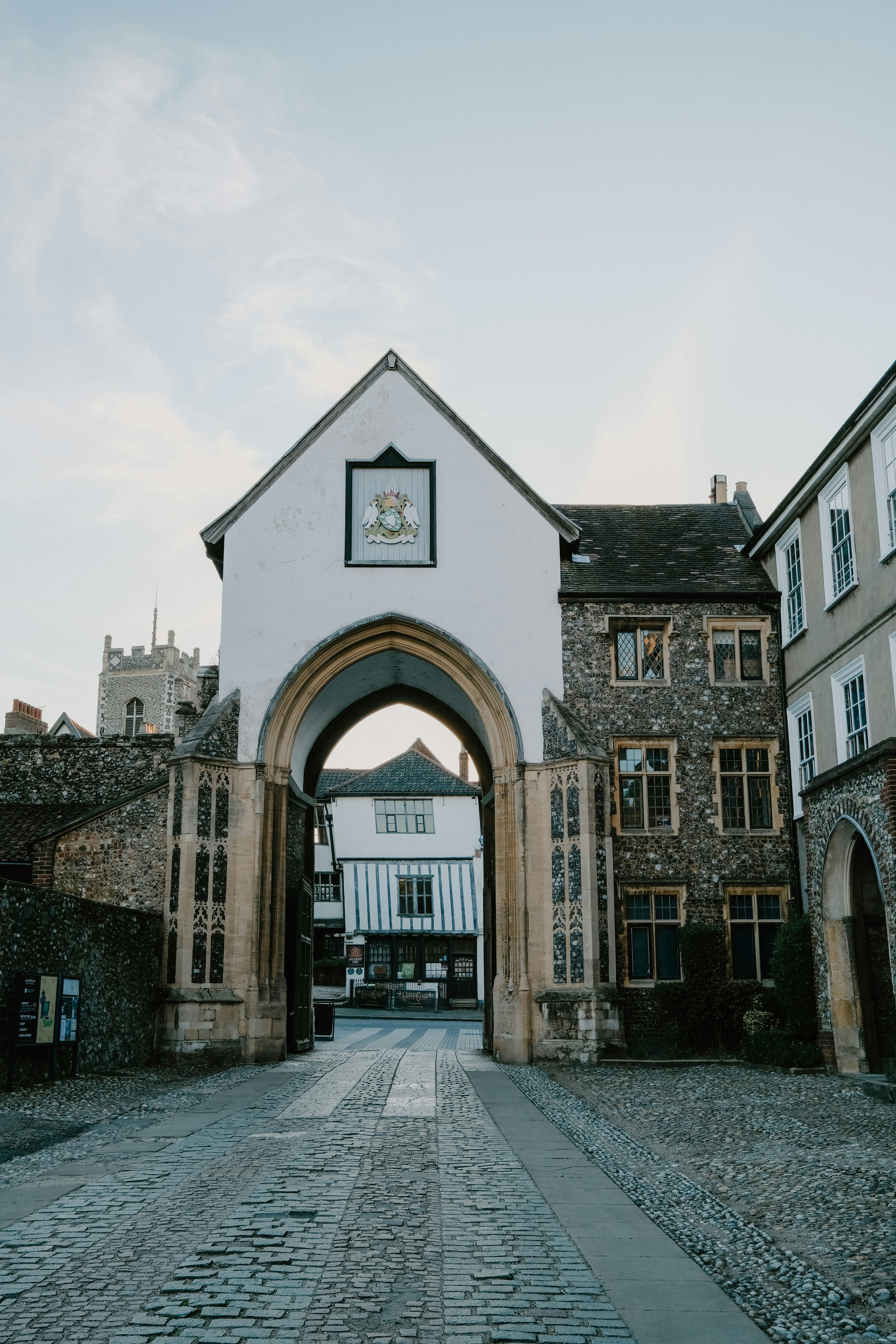 A stone archway leading to a historic street with timber-framed buildings