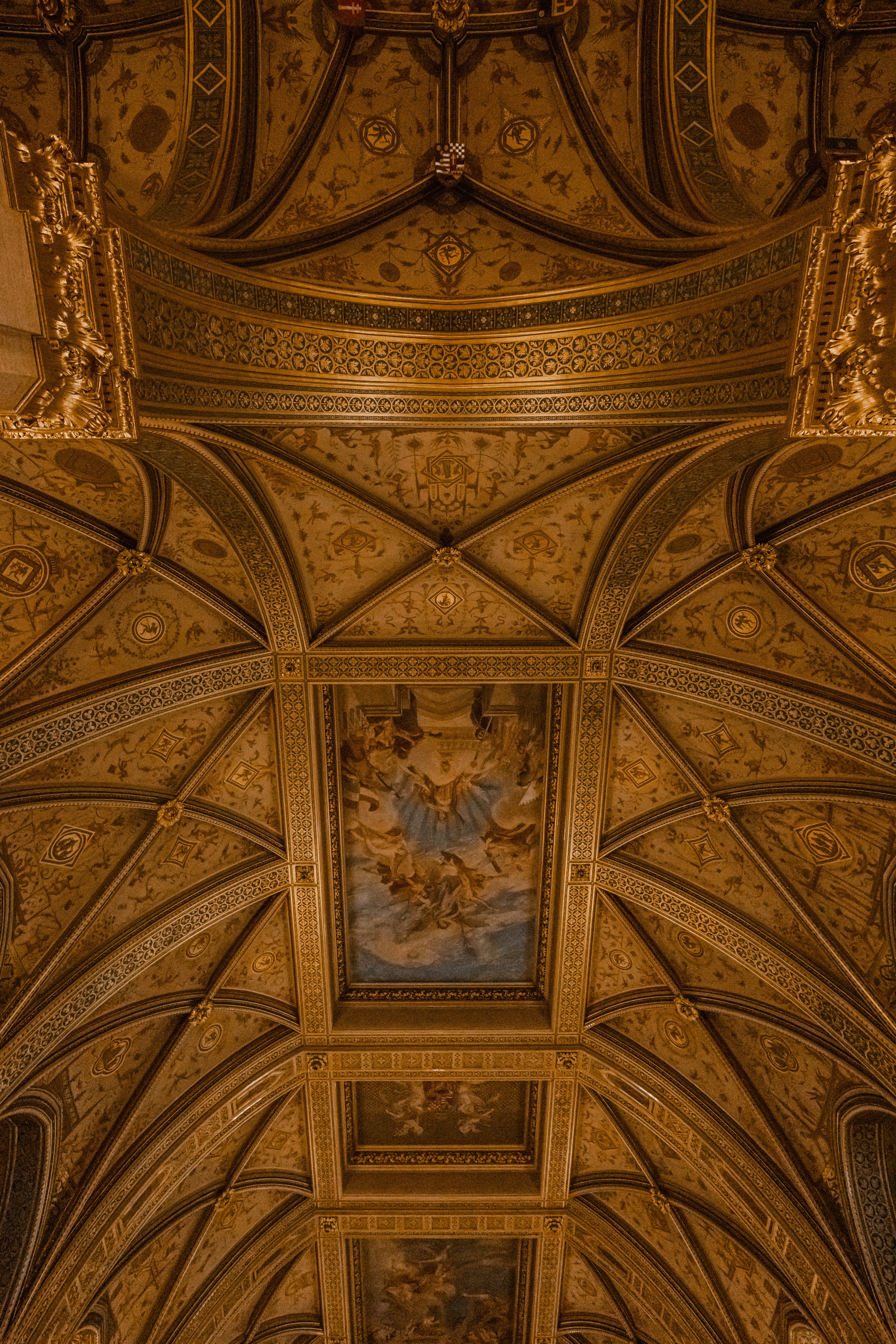 An ornate vaulted ceiling with gold detailing and inset paintings of figures