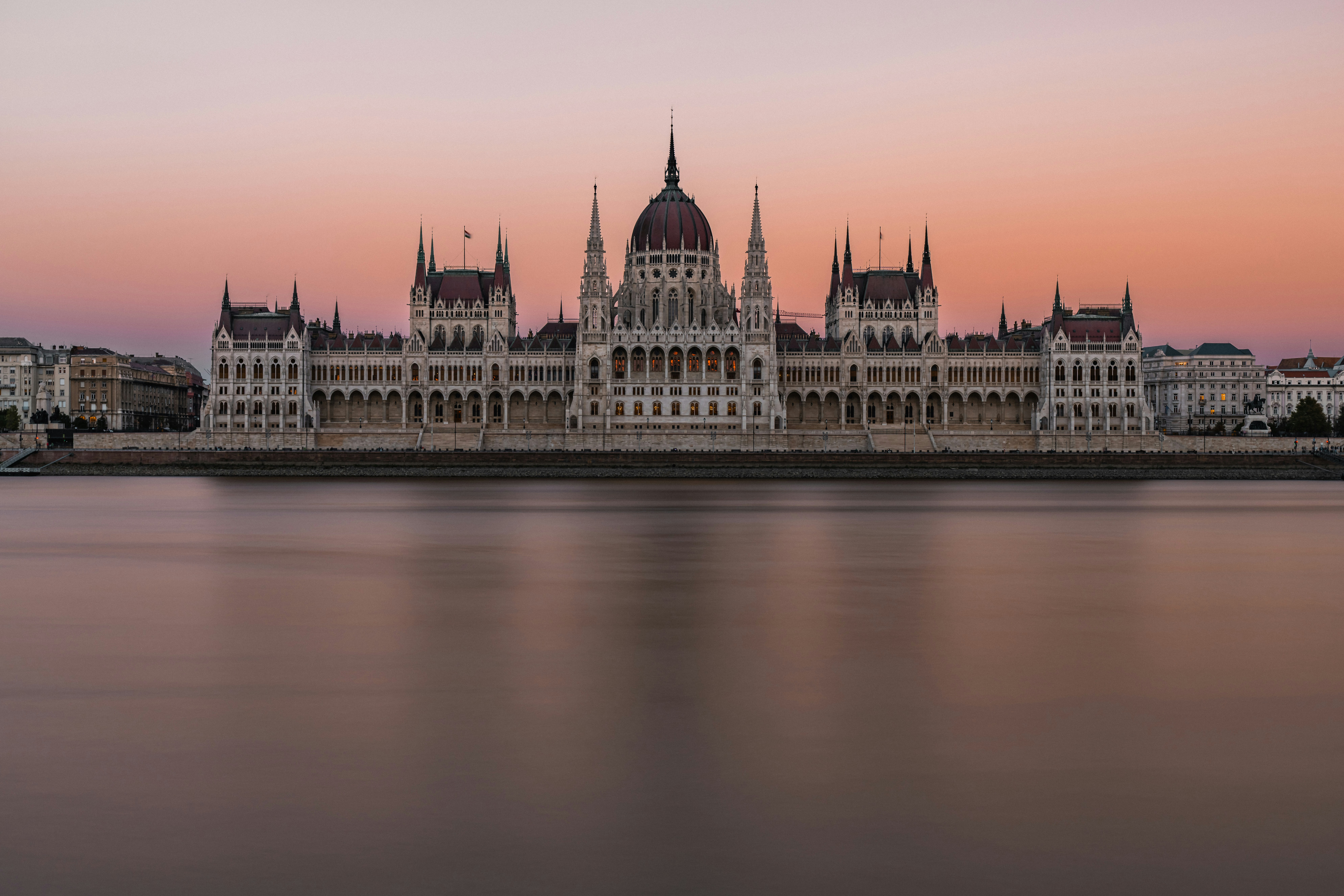 The Hungarian Parliament Building across the Danube river under a soft pink sky