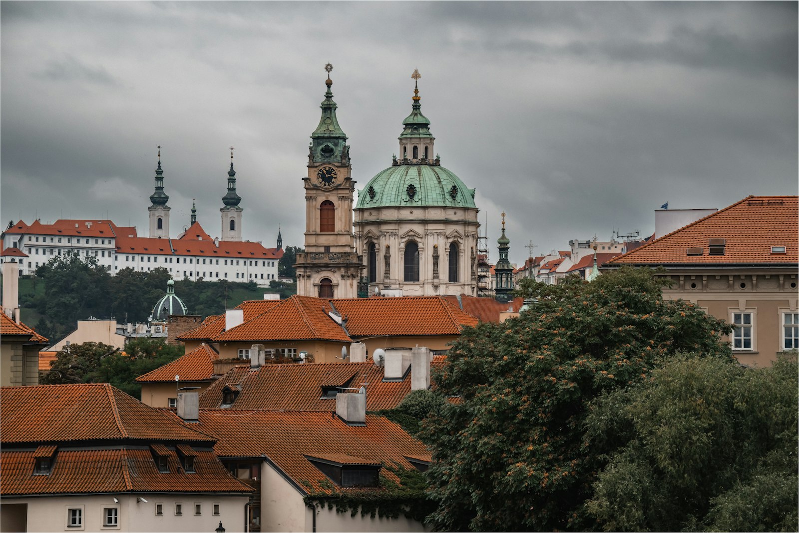 The green dome and tower of St. Nicholas Church above the red rooftops of Malá Strana