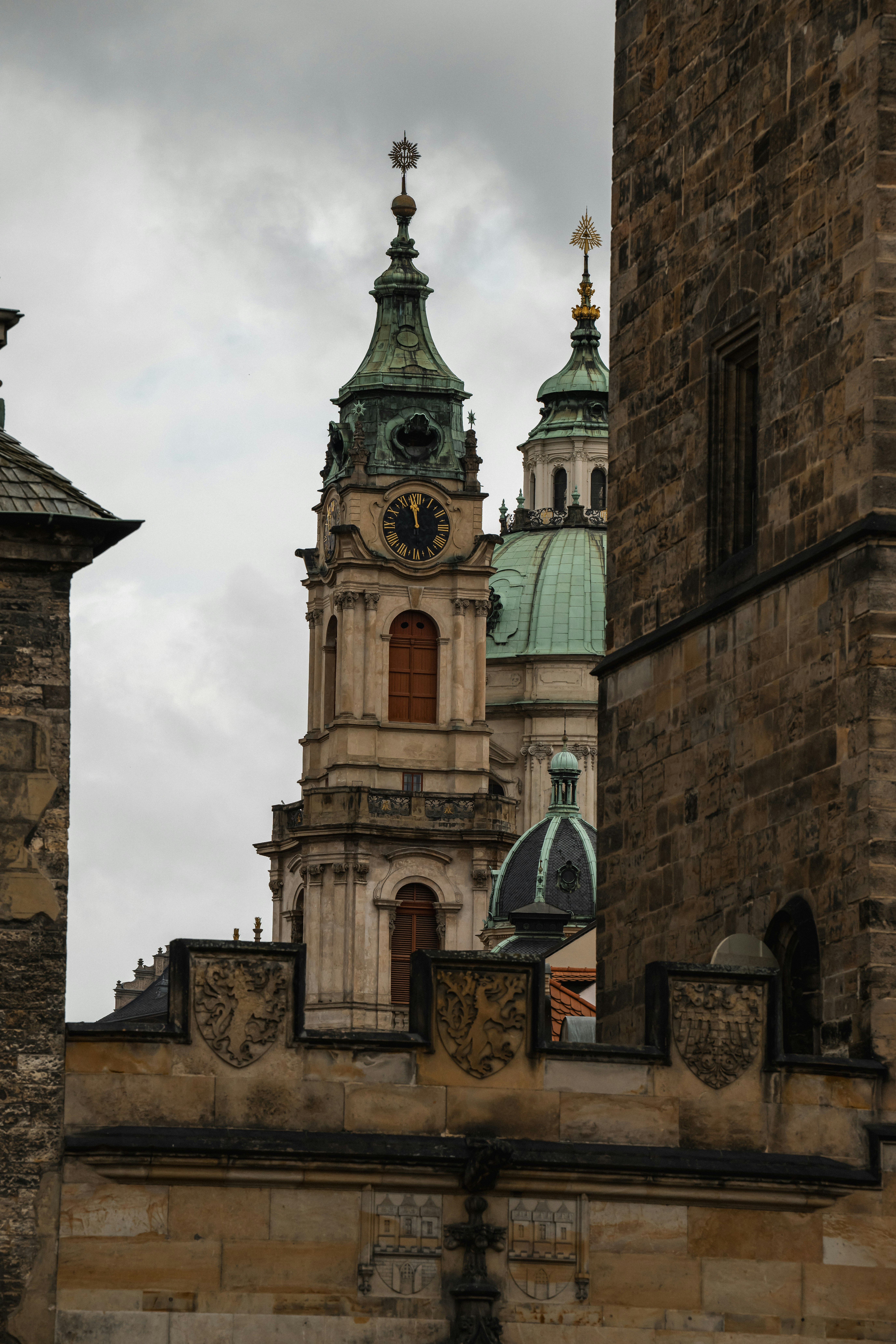 The clock tower and green dome of Saint Nicholas Church in Prague