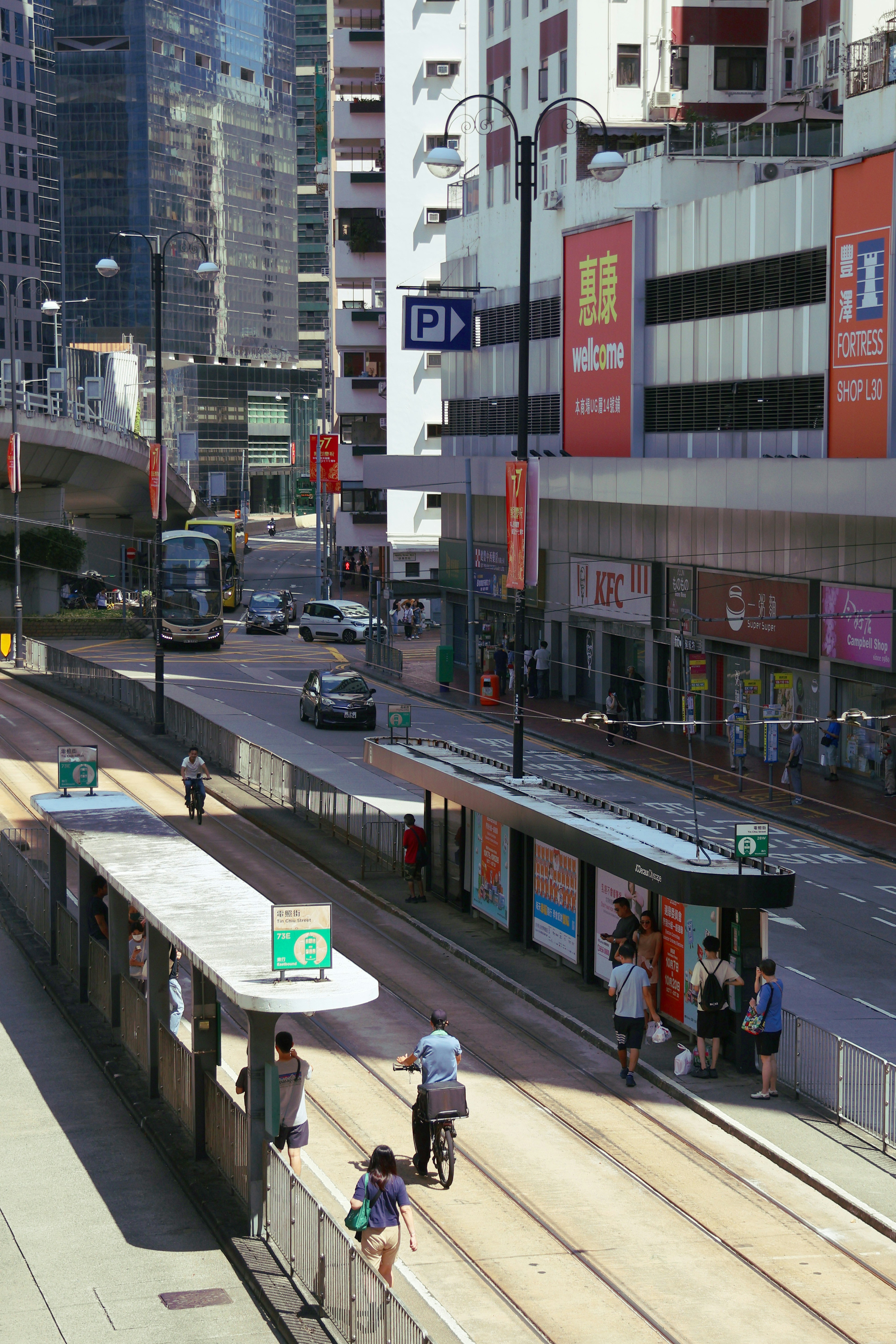 香港の交通量の多い通りのトラム停留所で待つ人々