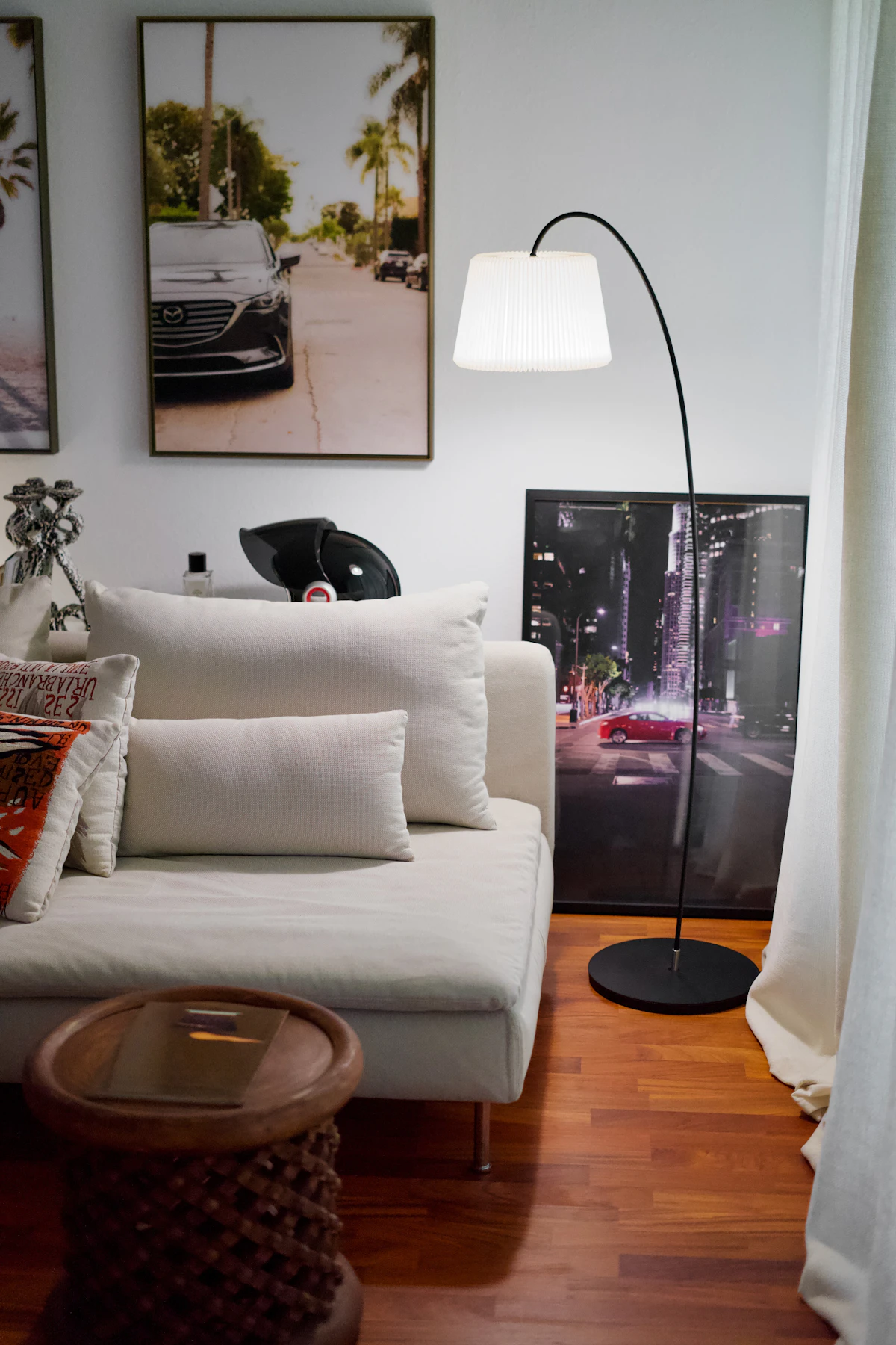 Slim floor lamp glowing beside a small lounge sofa