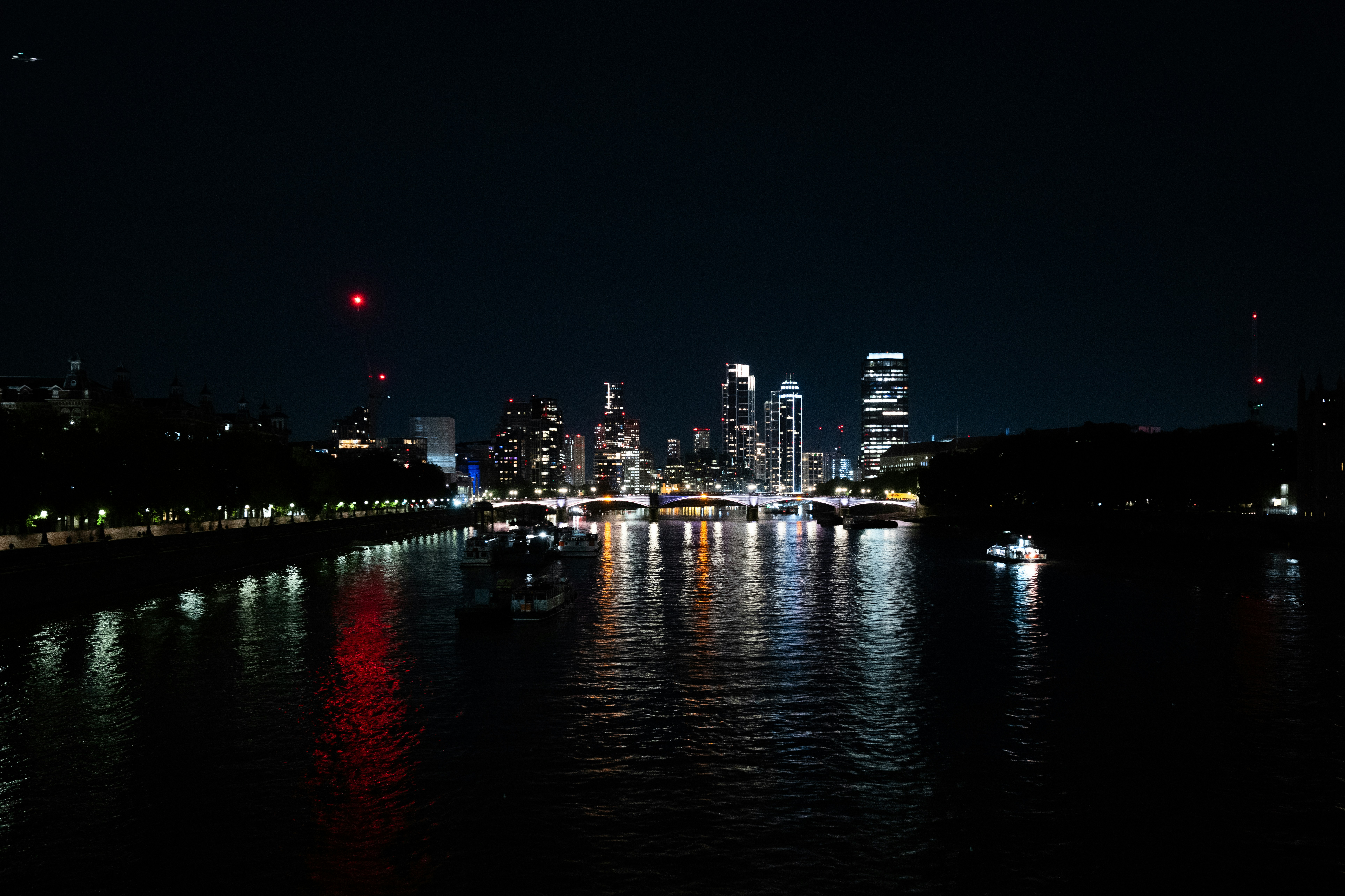 The London skyline at night with illuminated skyscrapers reflecting on the River Thames