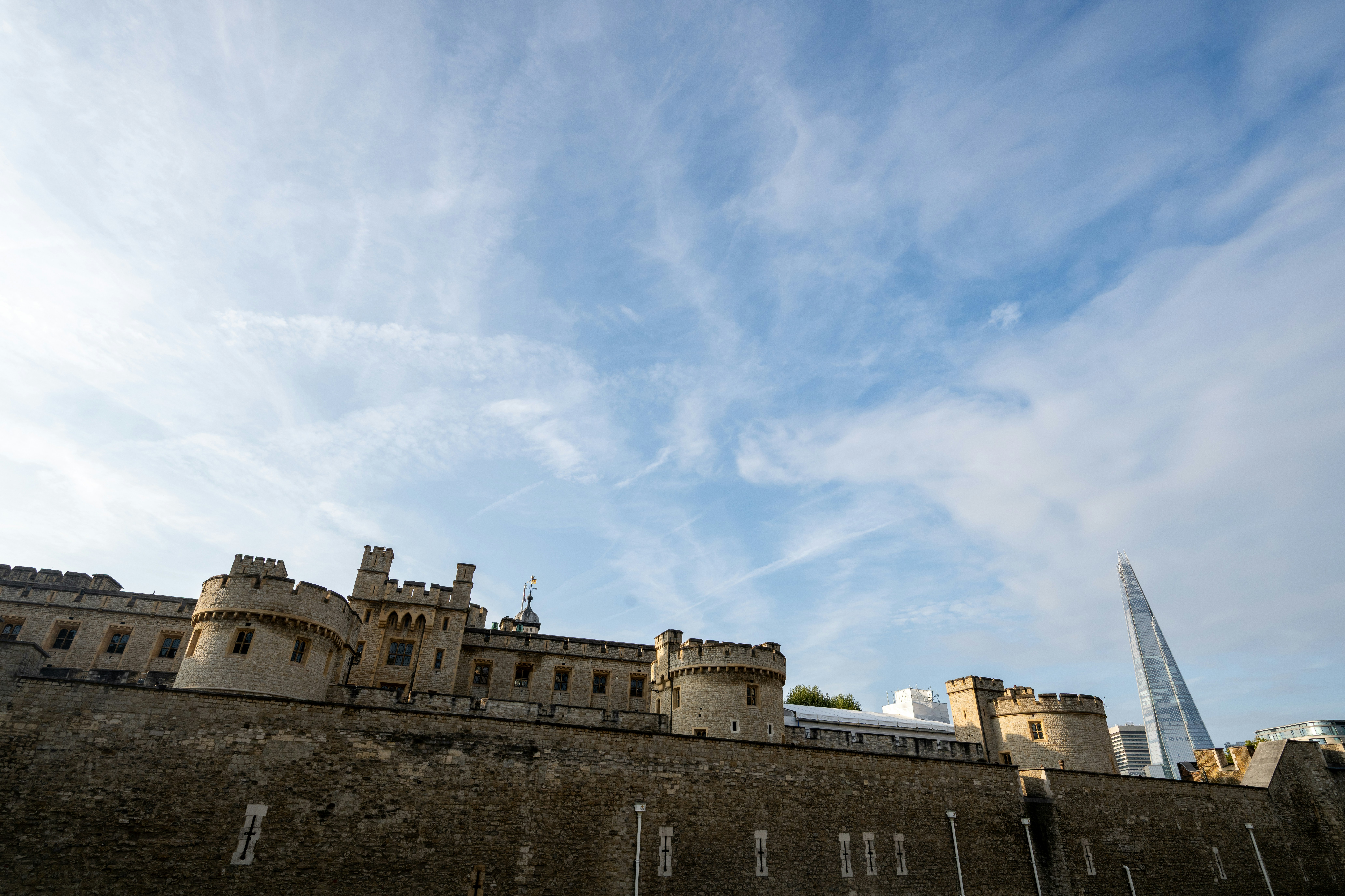 The Tower of London stone walls with The Shard skyscraper in the distance