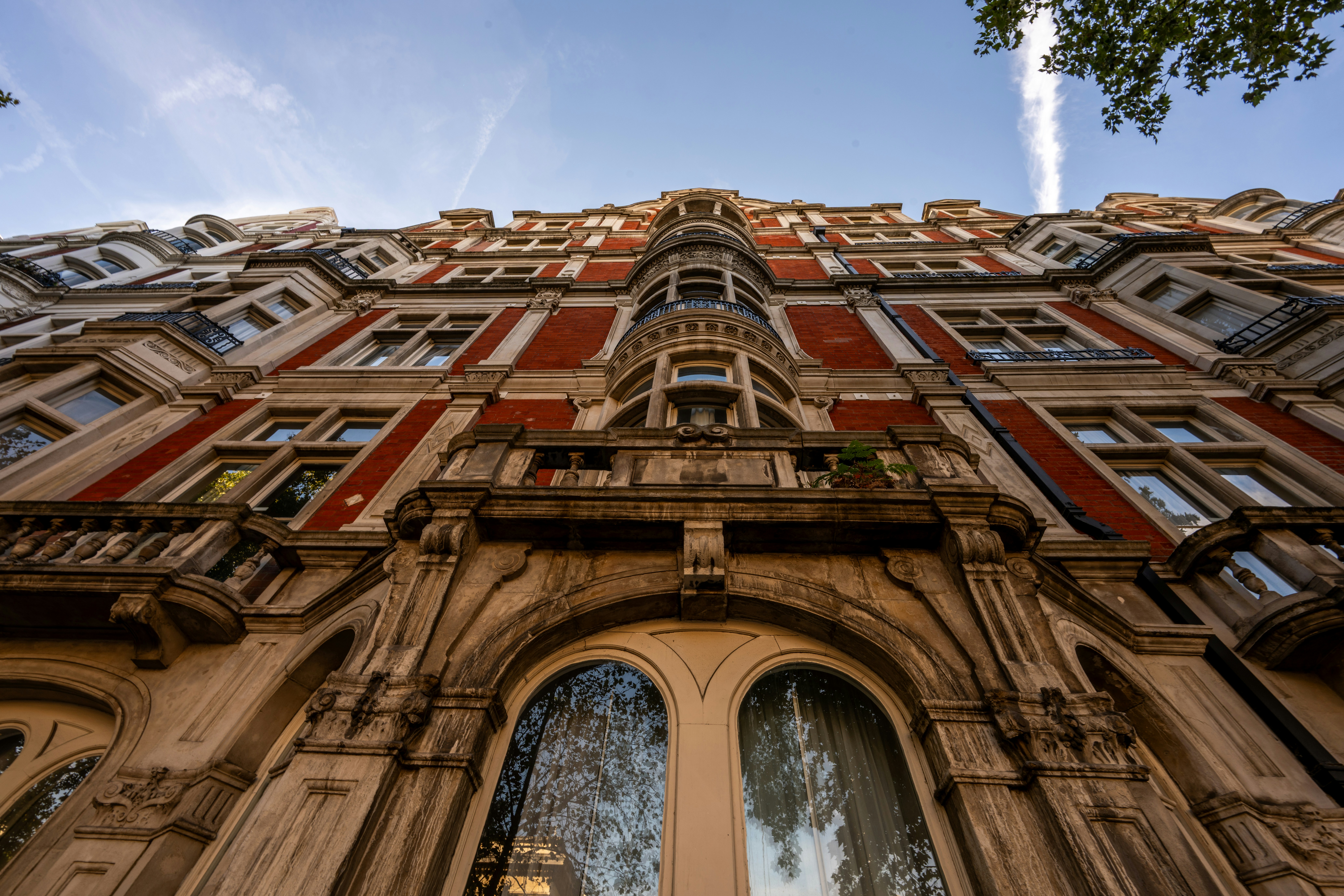 A low-angle view of a red brick building with ornate stone balconies and windows