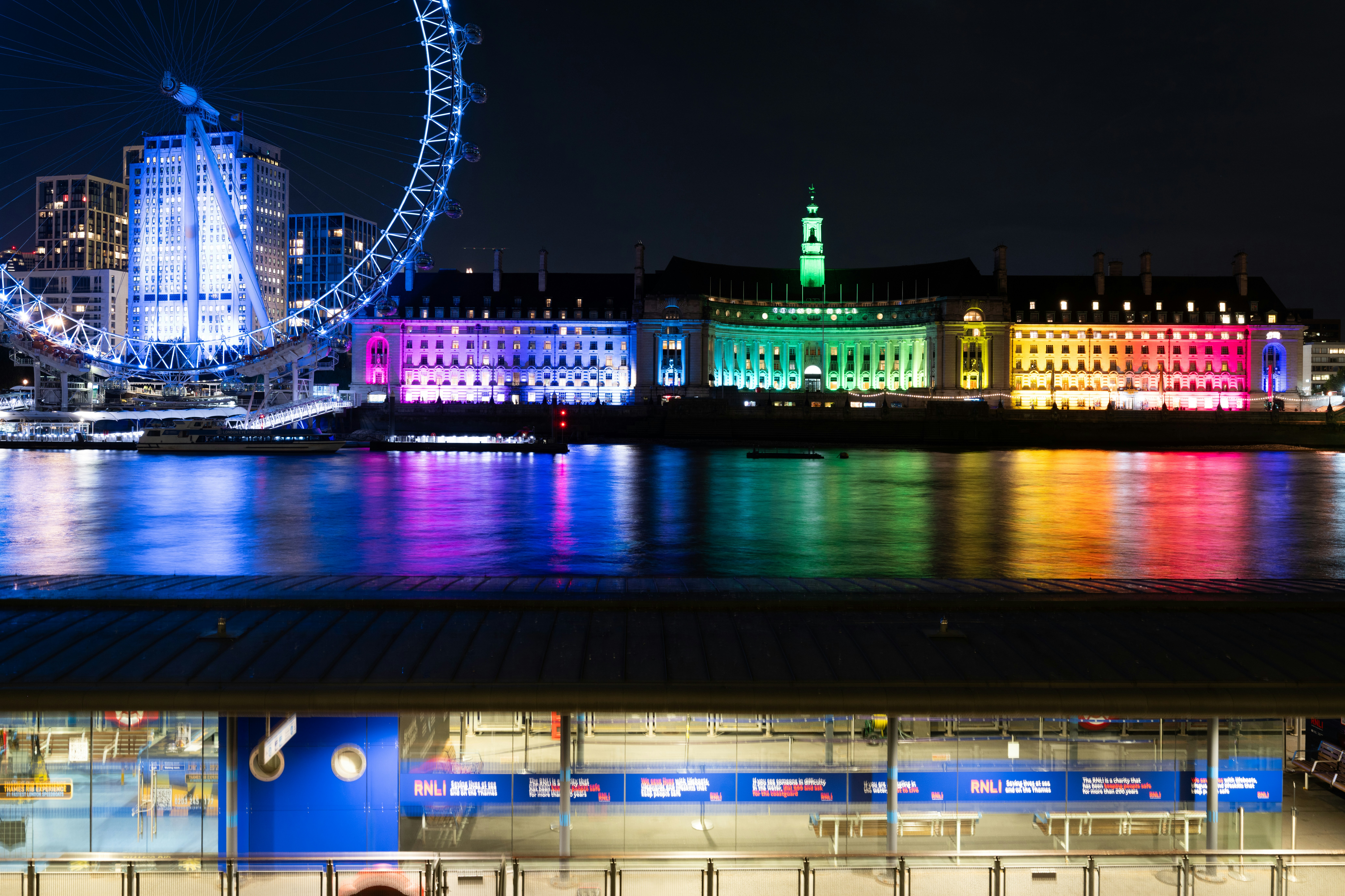 The London Eye and County Hall illuminated in rainbow colors at night in London