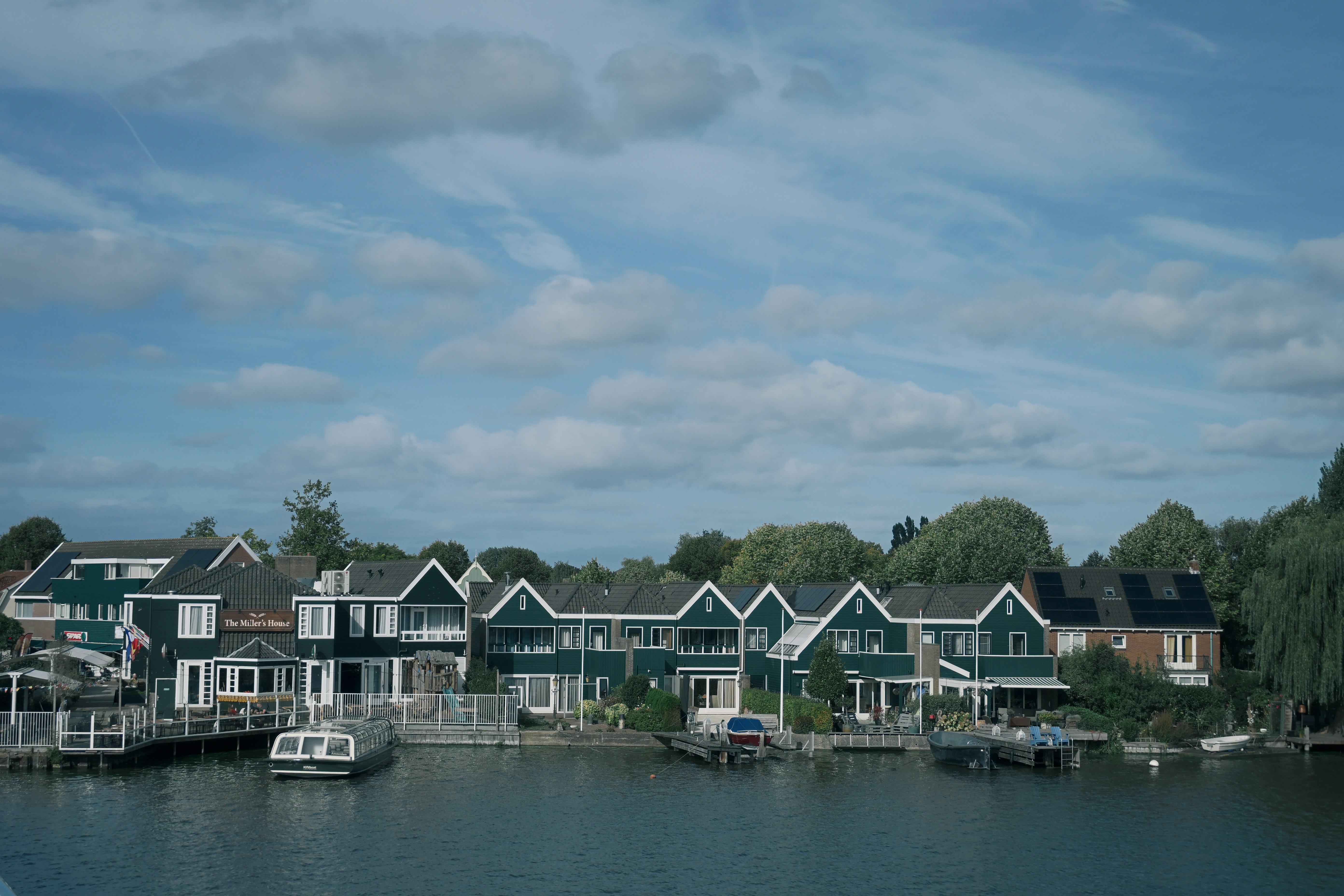 Green houses along a canal with boats moored at private docks