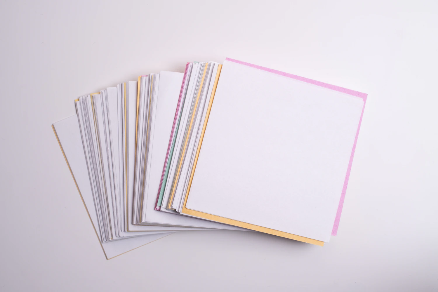 A fanned stack of 15 cm Studio Mix kami squares showing coloured edges