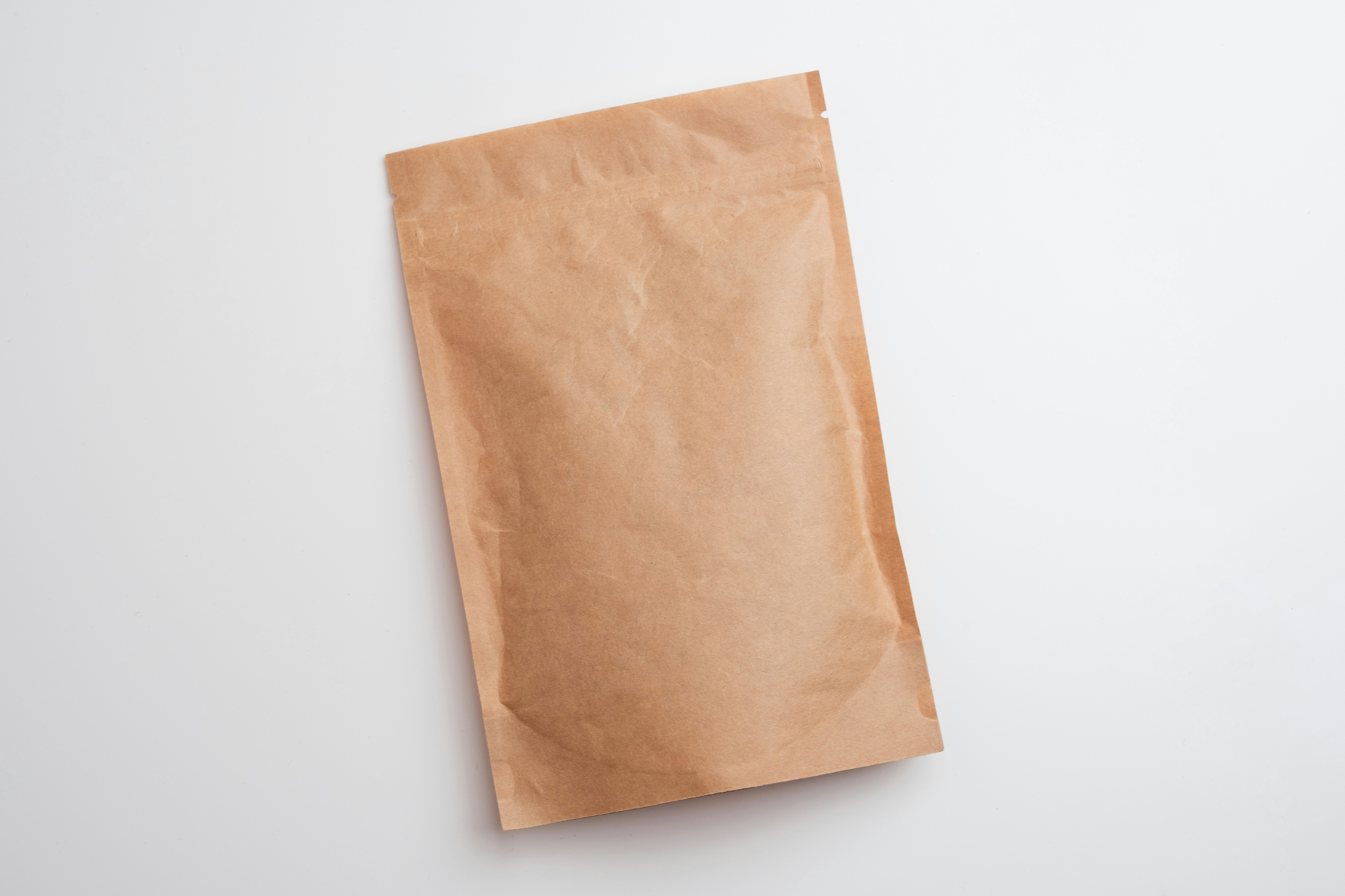 A brown paper pouch with a sealed top on a white background