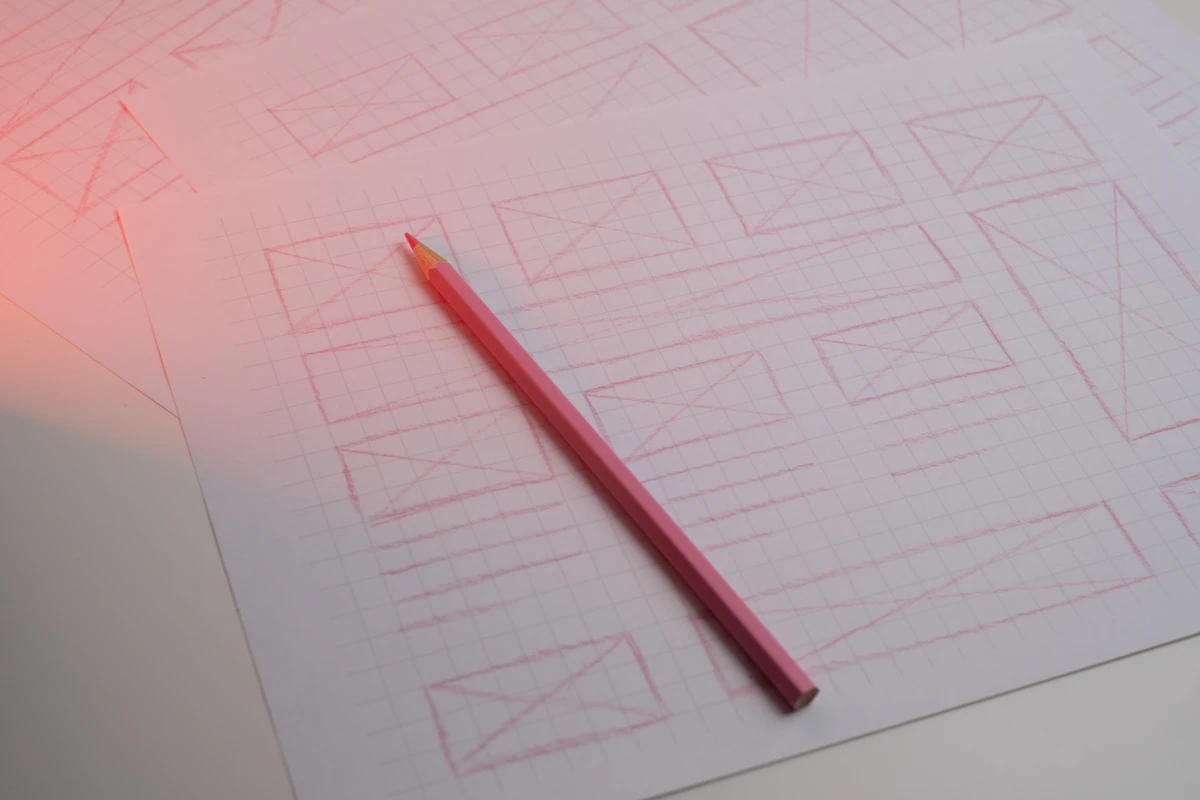 Pensil merah muda di atas kertas berpetak dengan sketsa tangan