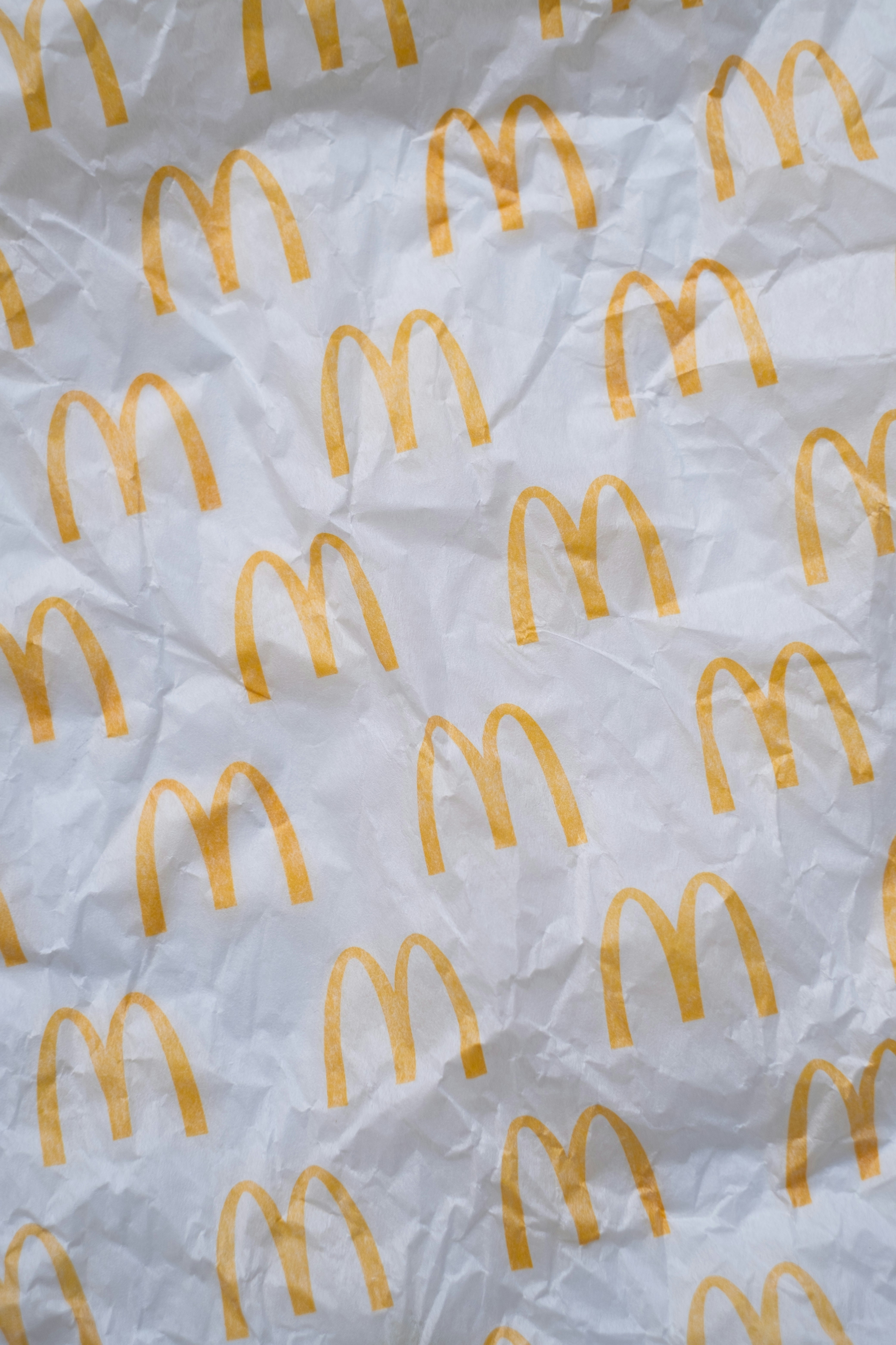Yellow golden arches logos printed in a repeating pattern on white crumpled paper