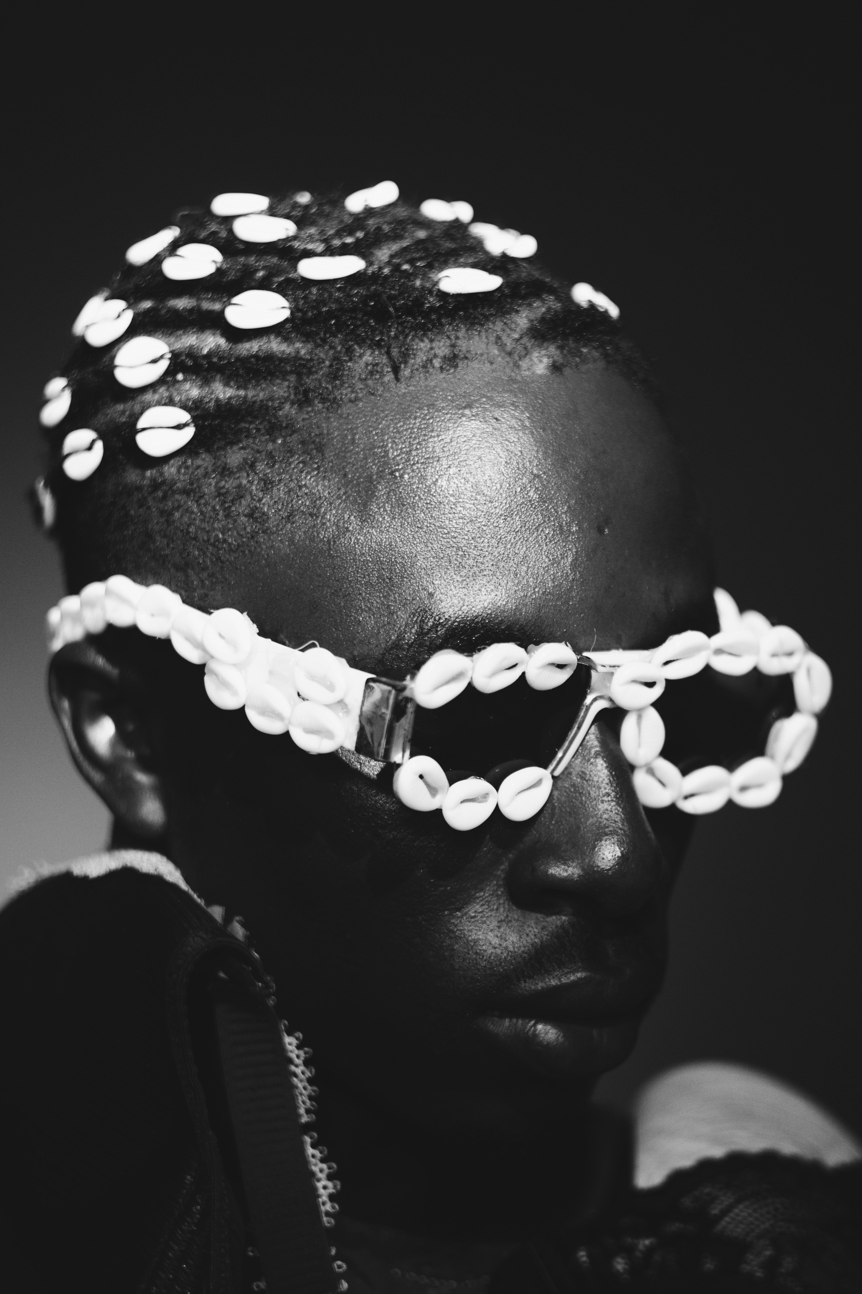 A person with cowrie shells in their hair and on their glasses