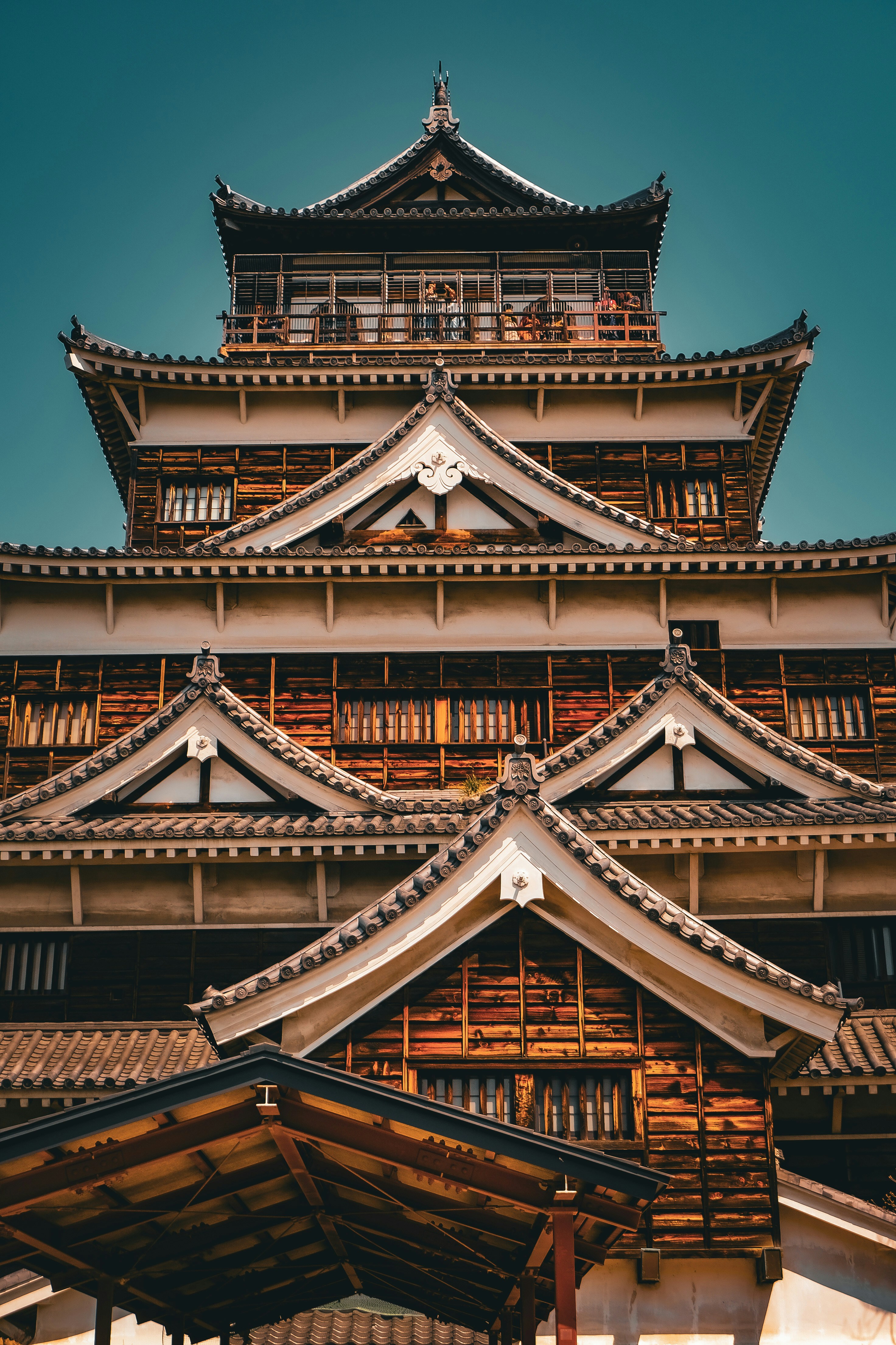 A traditional Japanese castle with dark wooden walls and tiered tiled roofs