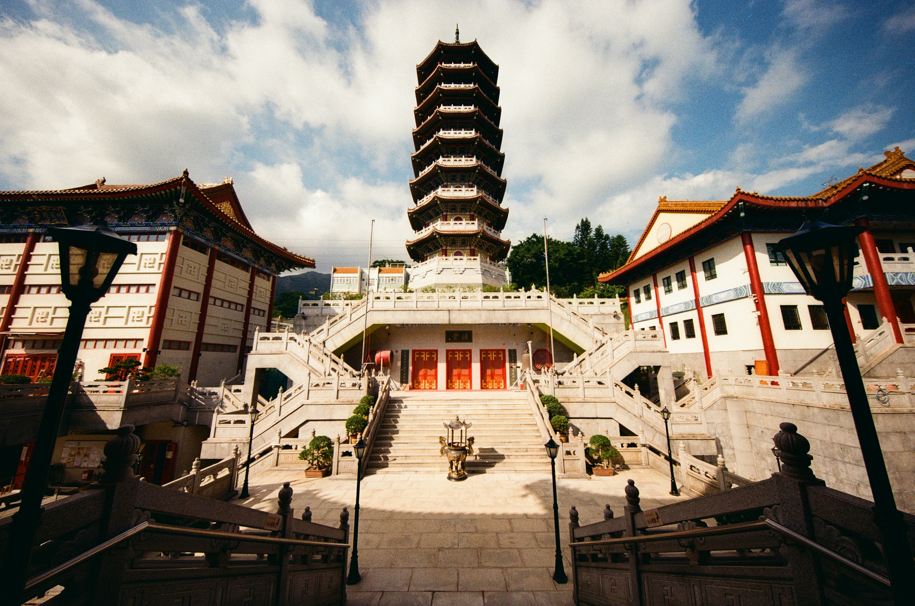 A tall pagoda rising above a stone courtyard with stairs and temple buildings