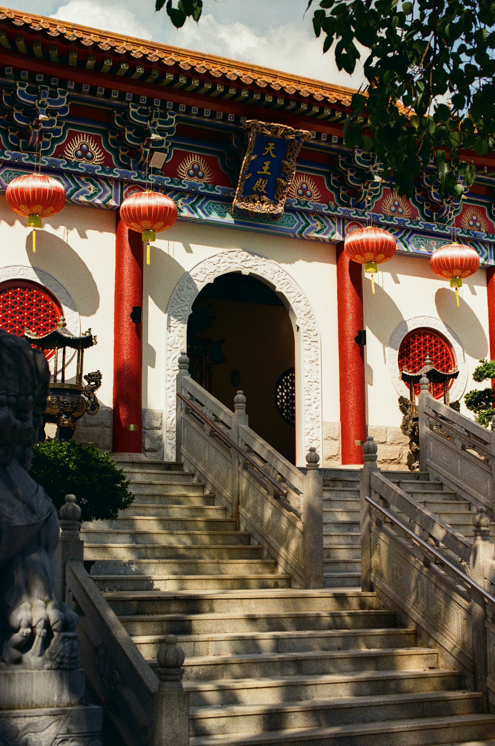 Stone stairs leading to a temple entrance with red lanterns and pillars