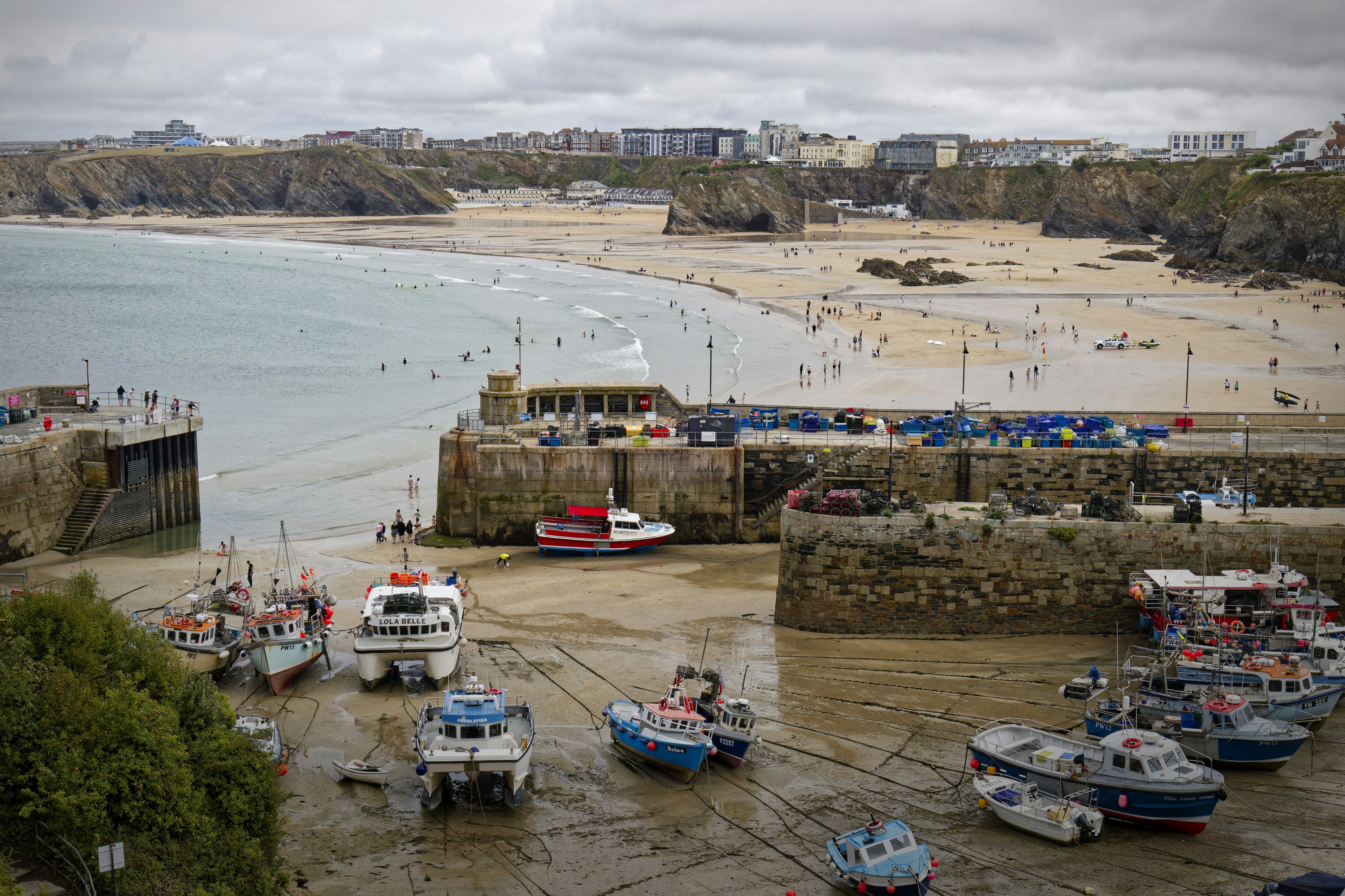 Fishing boats resting on the sandy harbor floor at low tide in Newquay