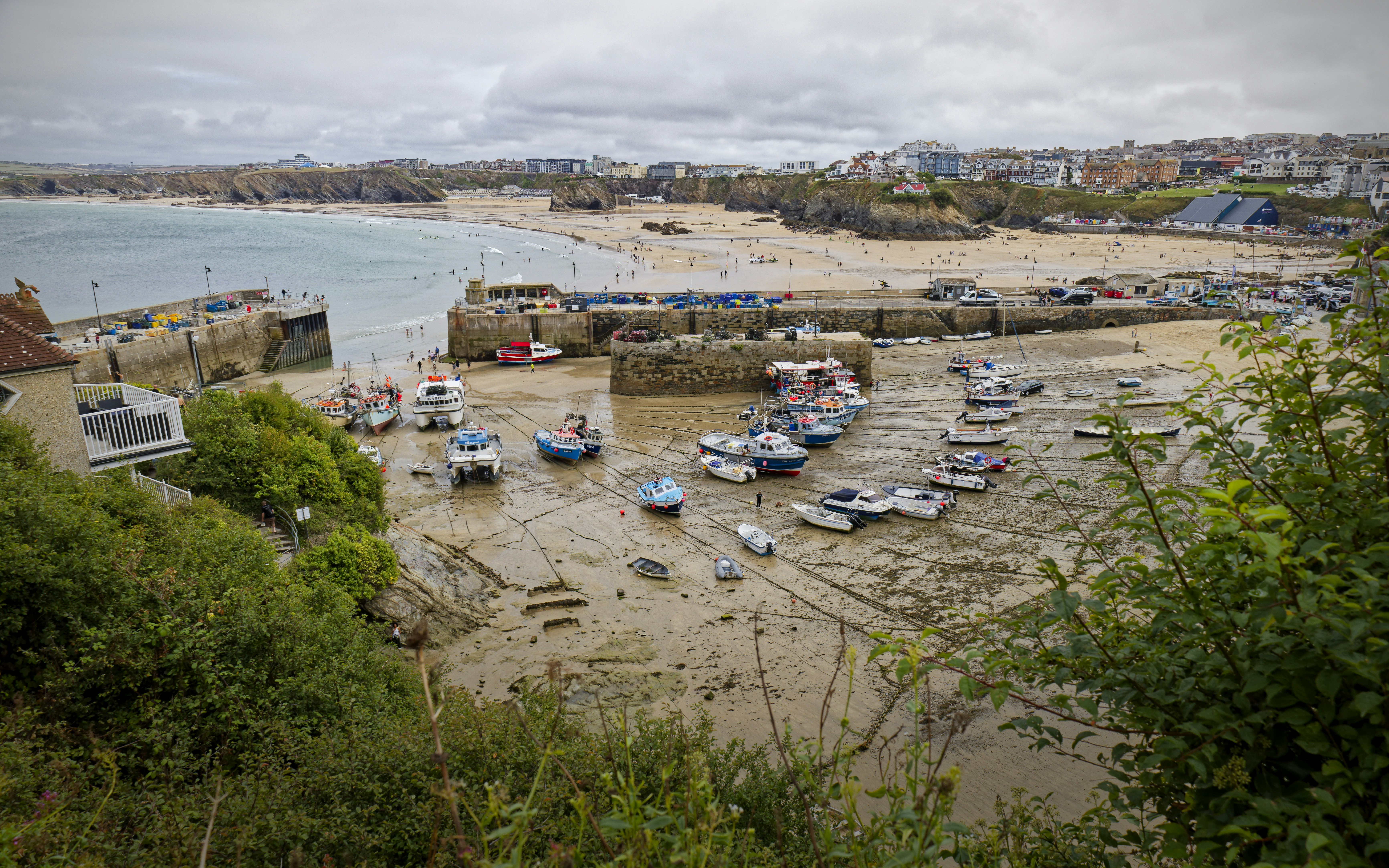 Fishing boats moored in a tidal harbor at low tide near a sandy beach
