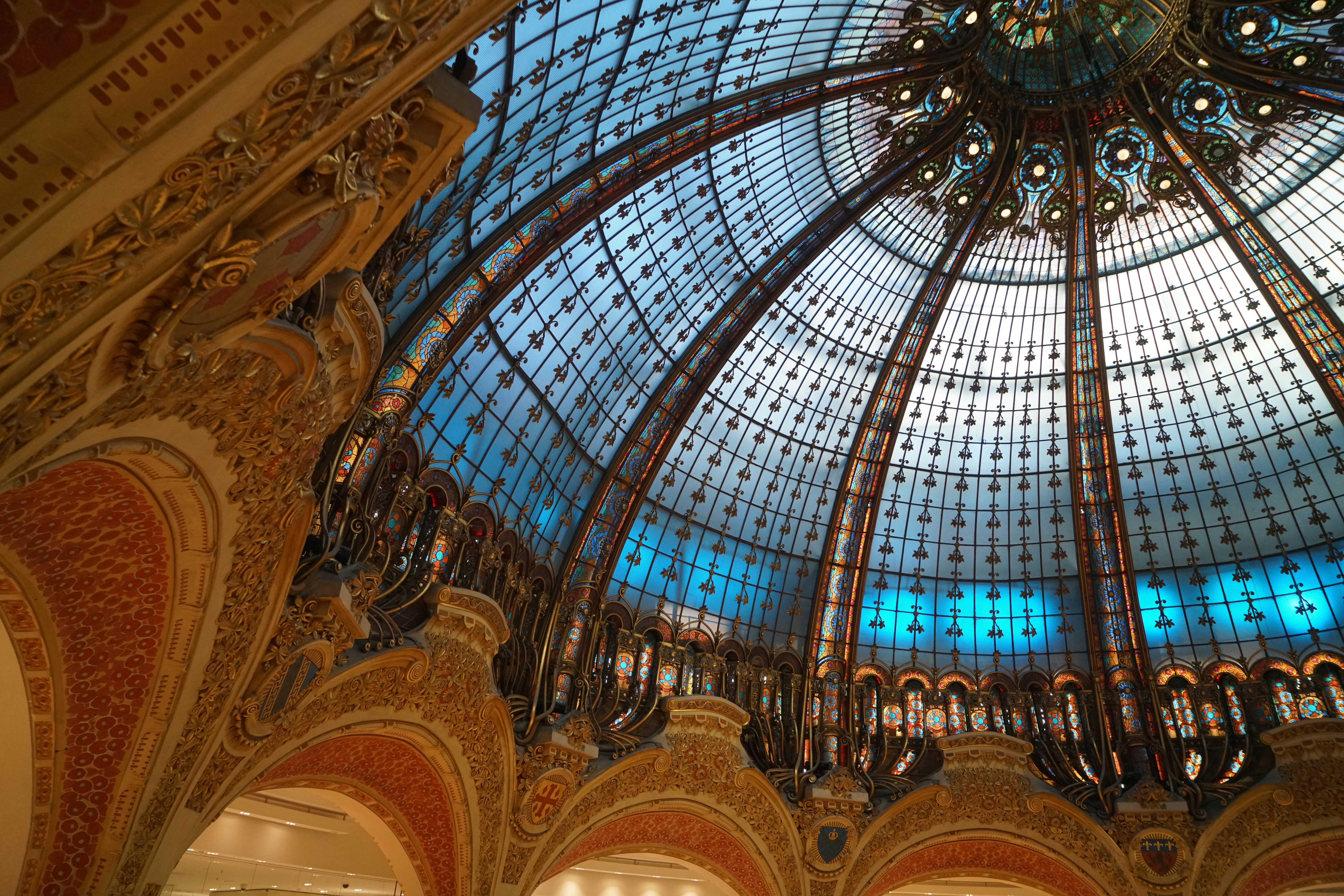 The ornate stained glass dome of Galeries Lafayette in Paris with intricate gold detailing