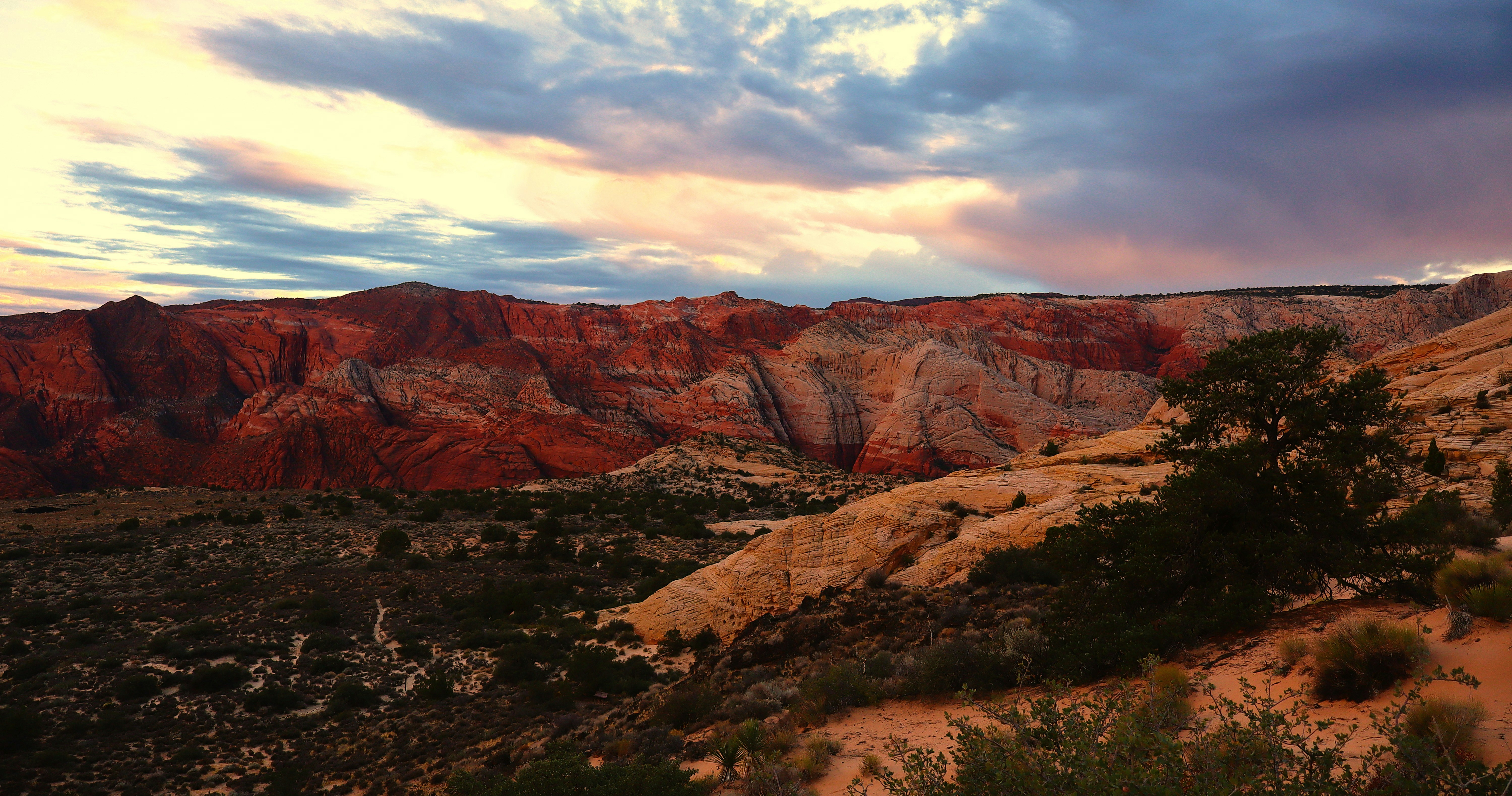 Red sandstone cliffs under a cloudy sky with low golden light