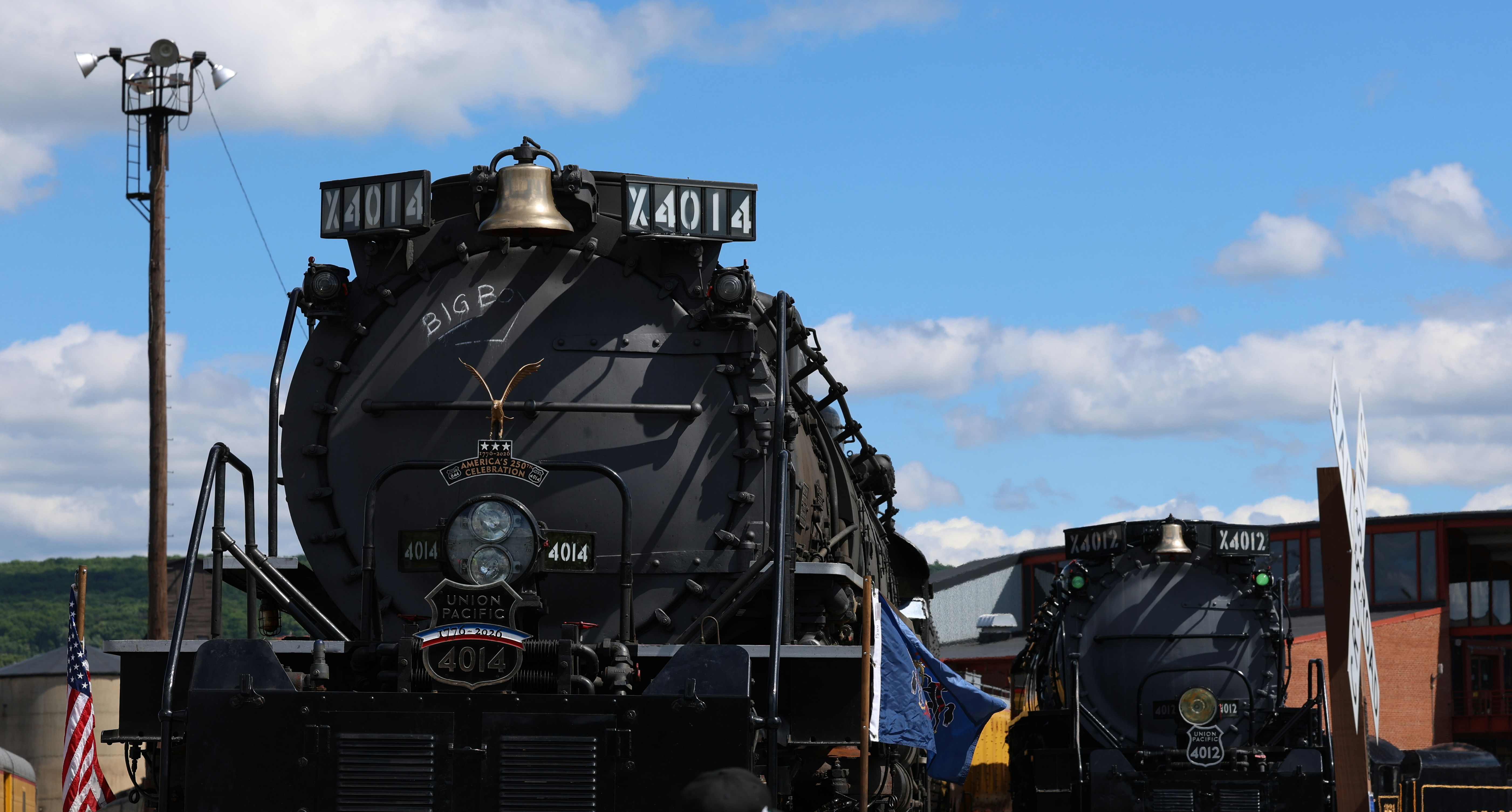 Two black Union Pacific steam locomotives parked outdoors under a bright blue sky