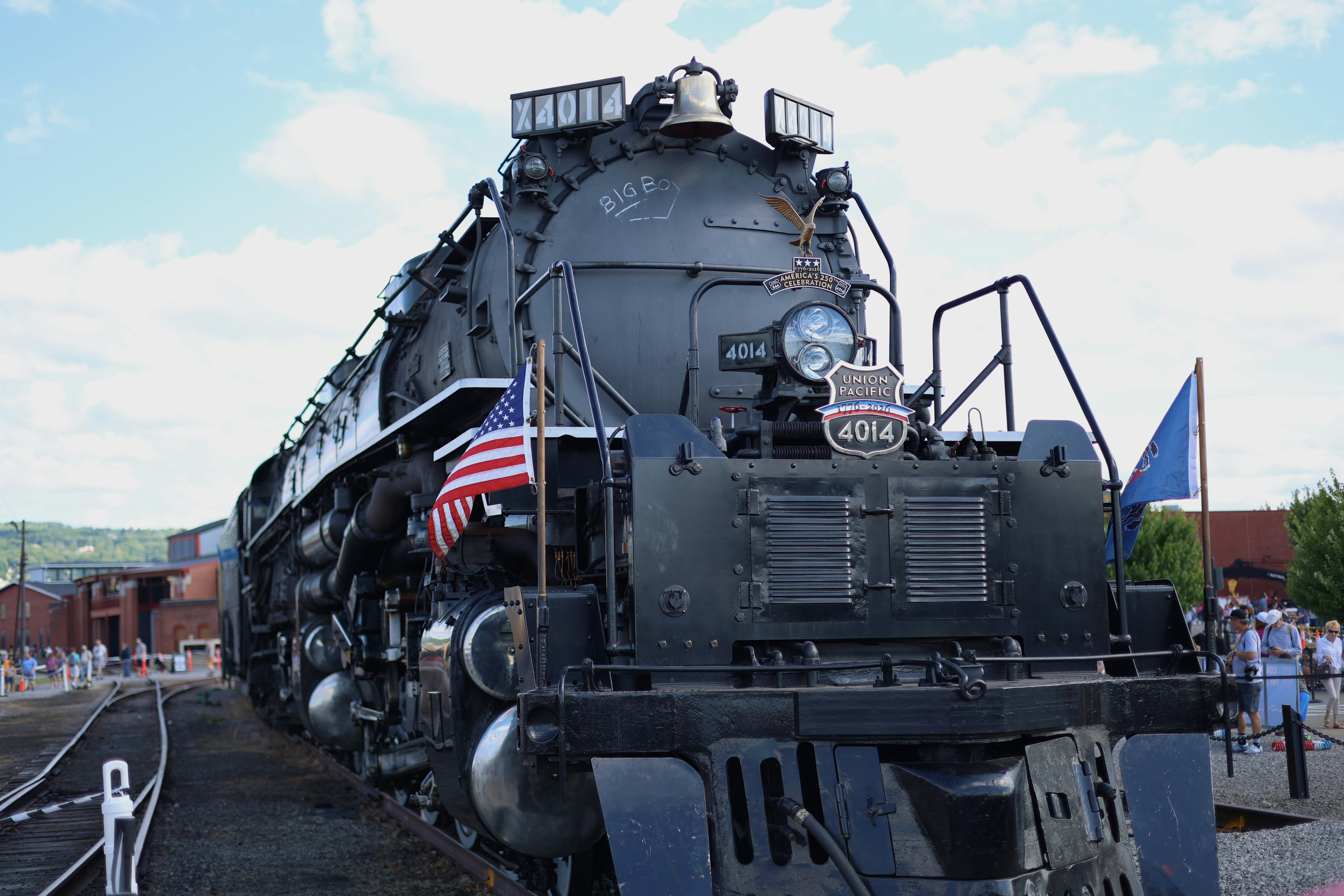 A black Union Pacific 4014 steam locomotive with an American flag on the tracks